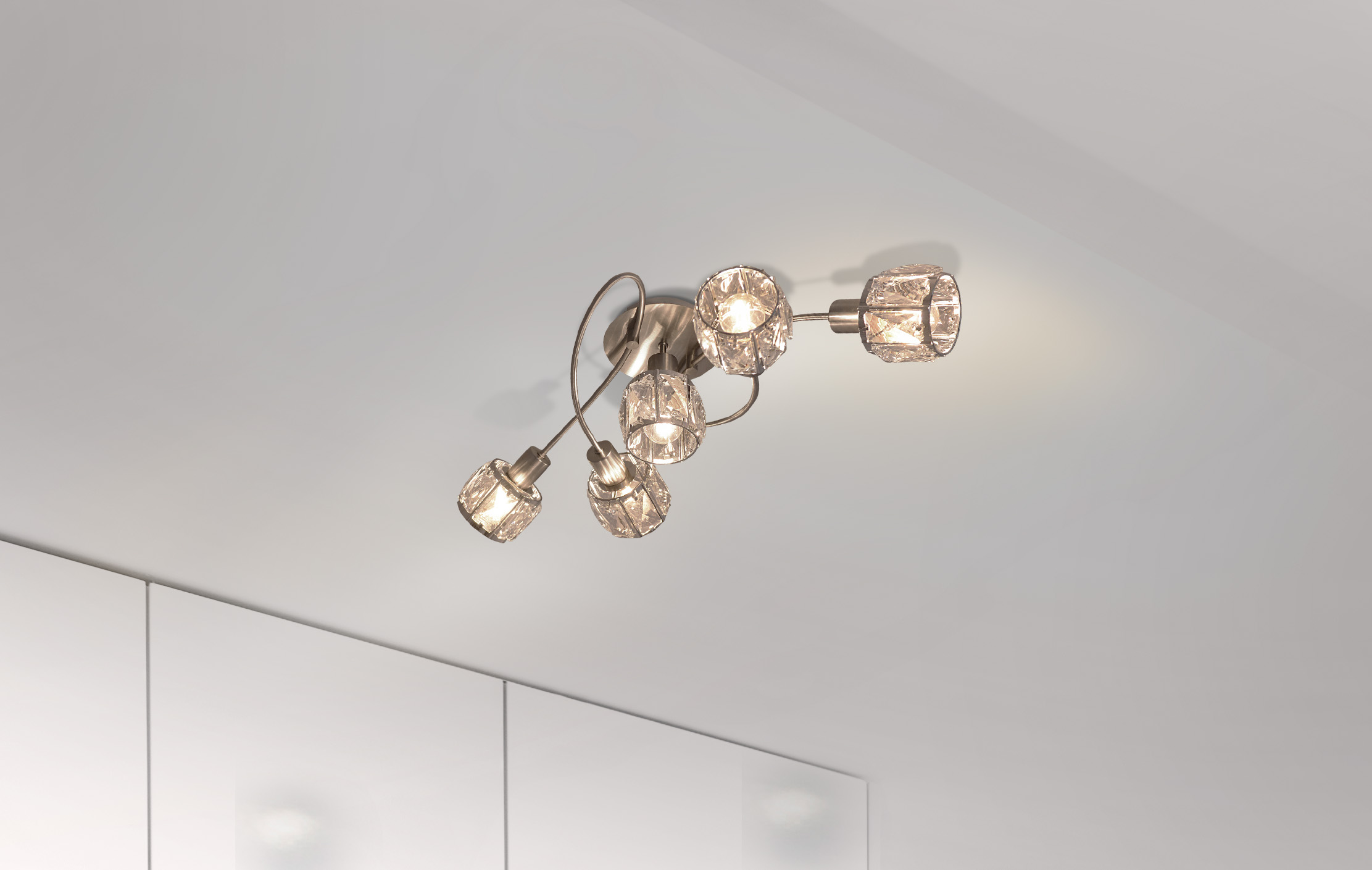 Deckenlampe mit fünf kristallinen Schirmen. Montiert an einer weißen Decke. Der Raum ist weiß.