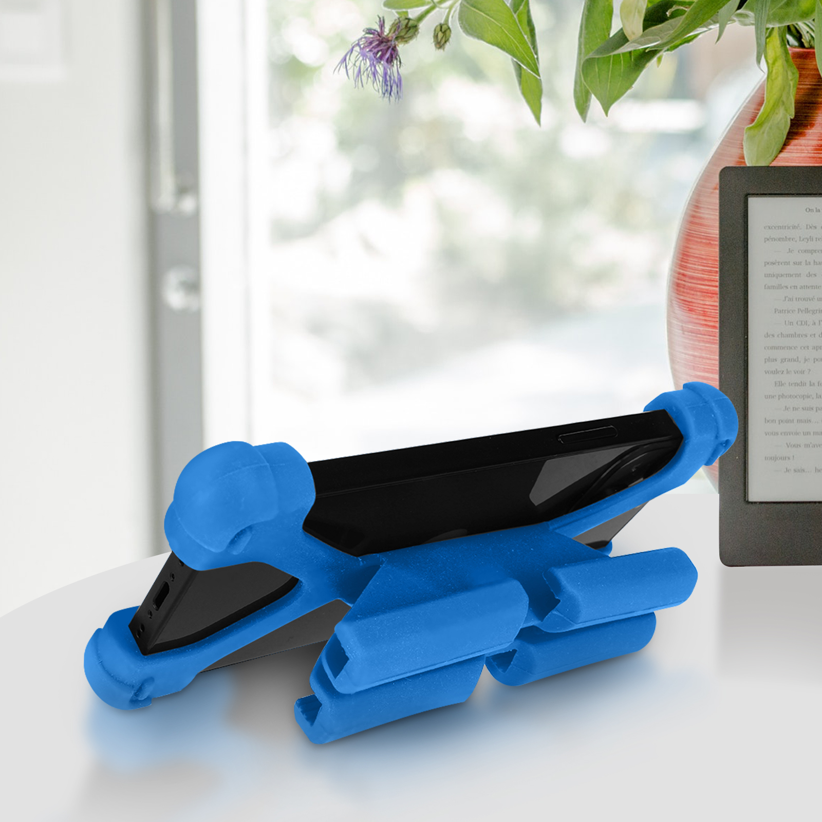 Ein schwarzes Telefon wird von einem blauen Telefonständer gehalten. Der Ständer hat die Form eines futuristischen Fahrzeugs.