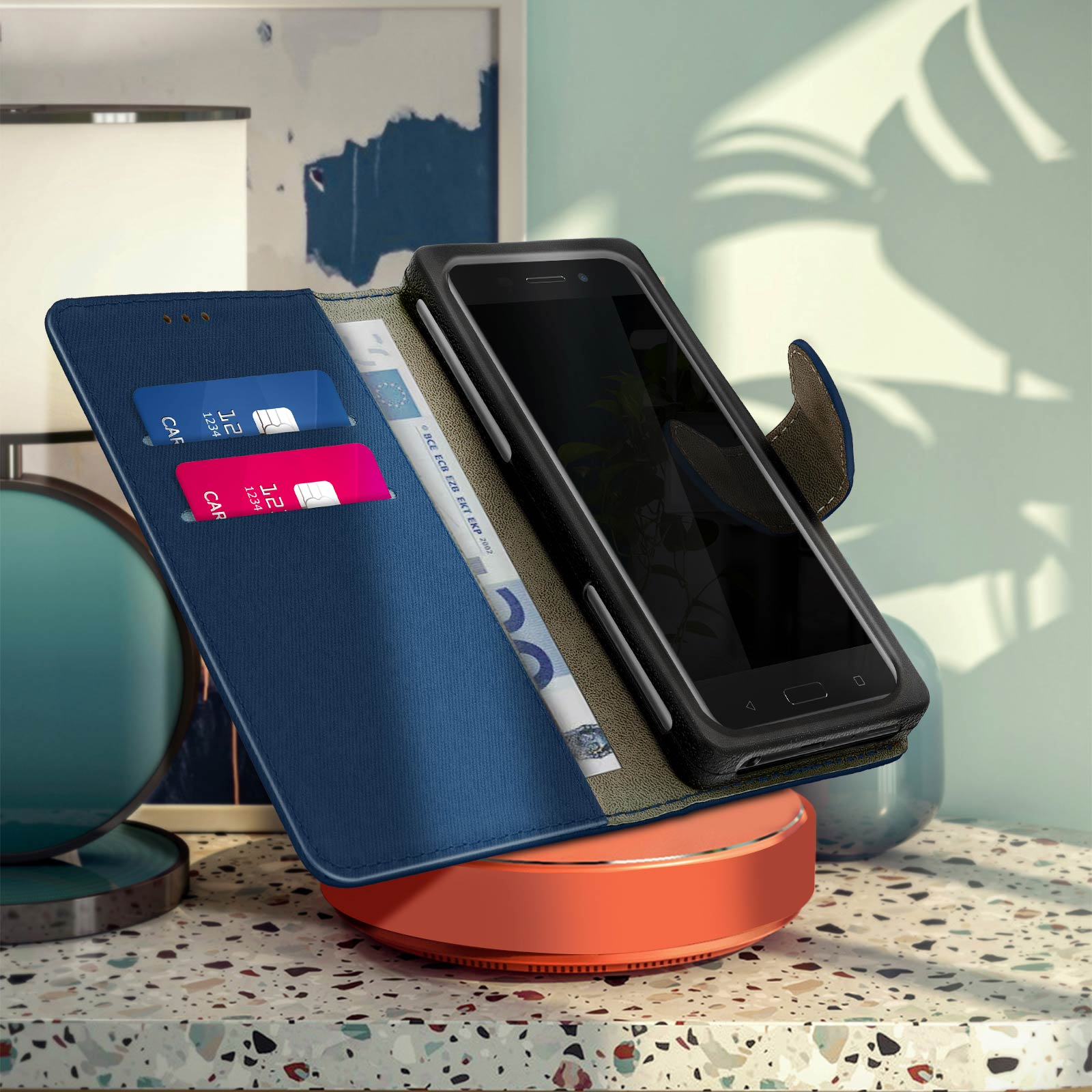 Un telefono in una custodia blu su un caricabatterie wireless, con carte e contanti visibili.