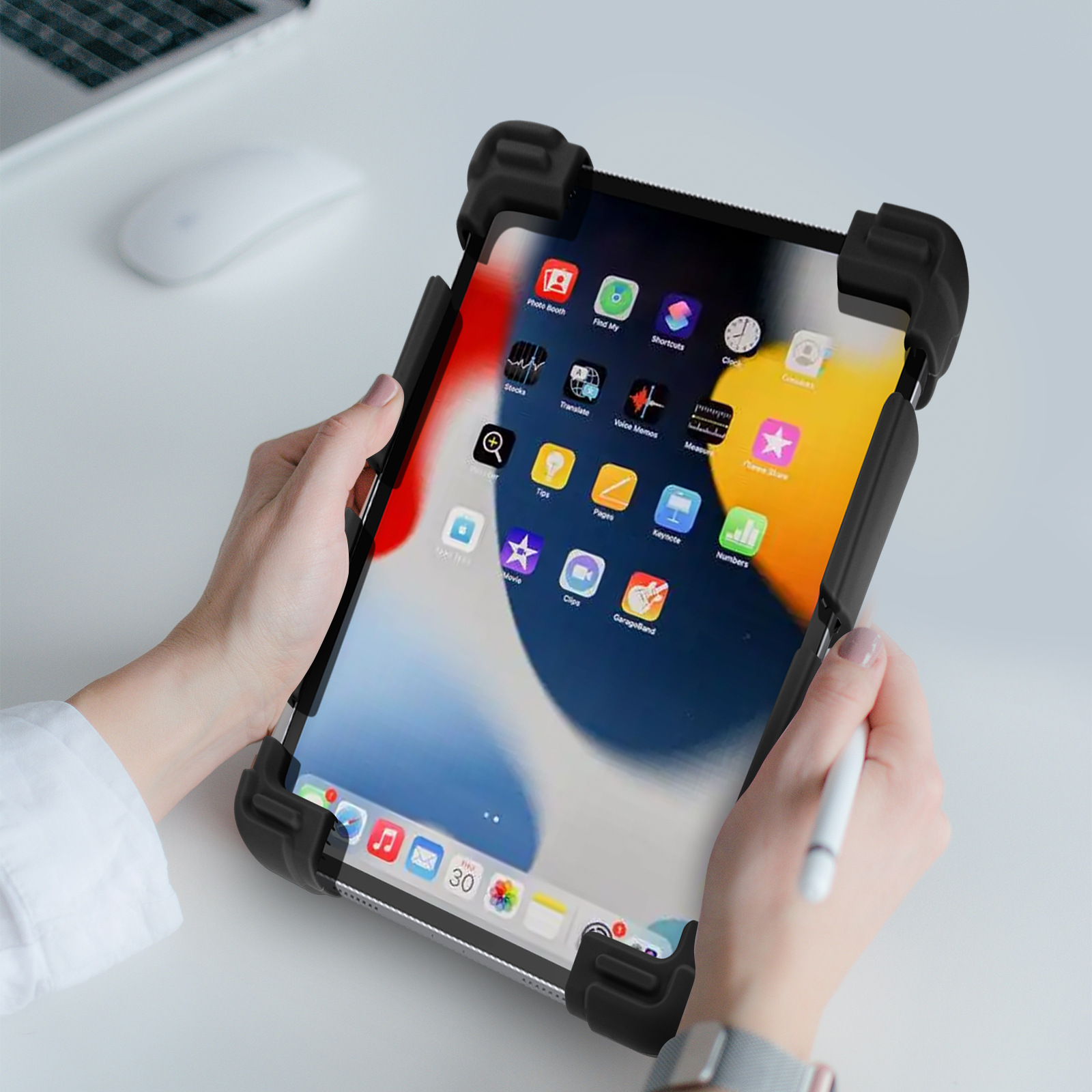 Hände halten ein iPad in einer schwarzen Hülle, weißer Schreibtisch mit Maus.