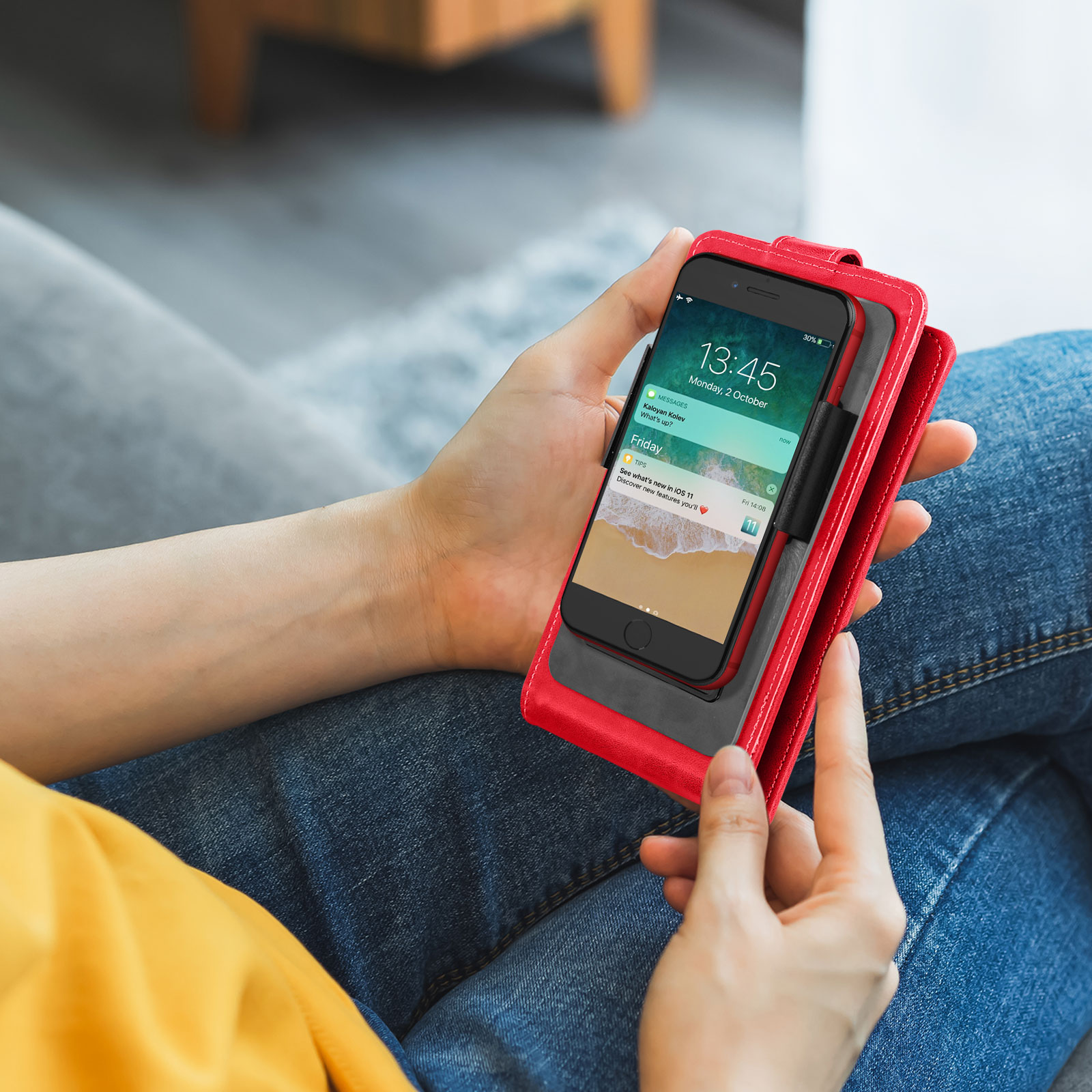 Una persona che tiene un telefono in una custodia a portafoglio in pelle rossa. Il telefono mostra la data e l'ora.