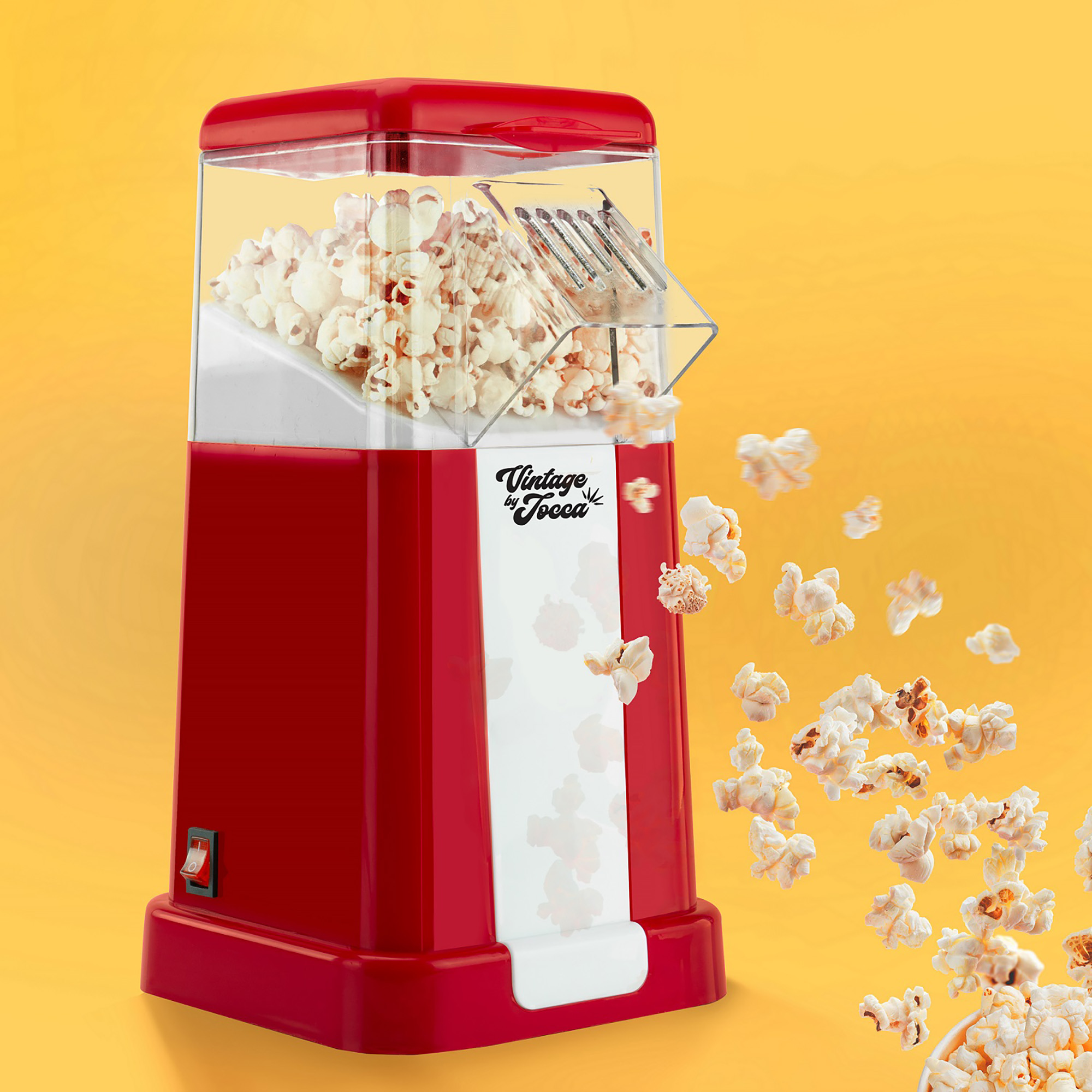 Macchina per popcorn rossa con dettagli bianchi, popcorn che escono su uno sfondo giallo.
