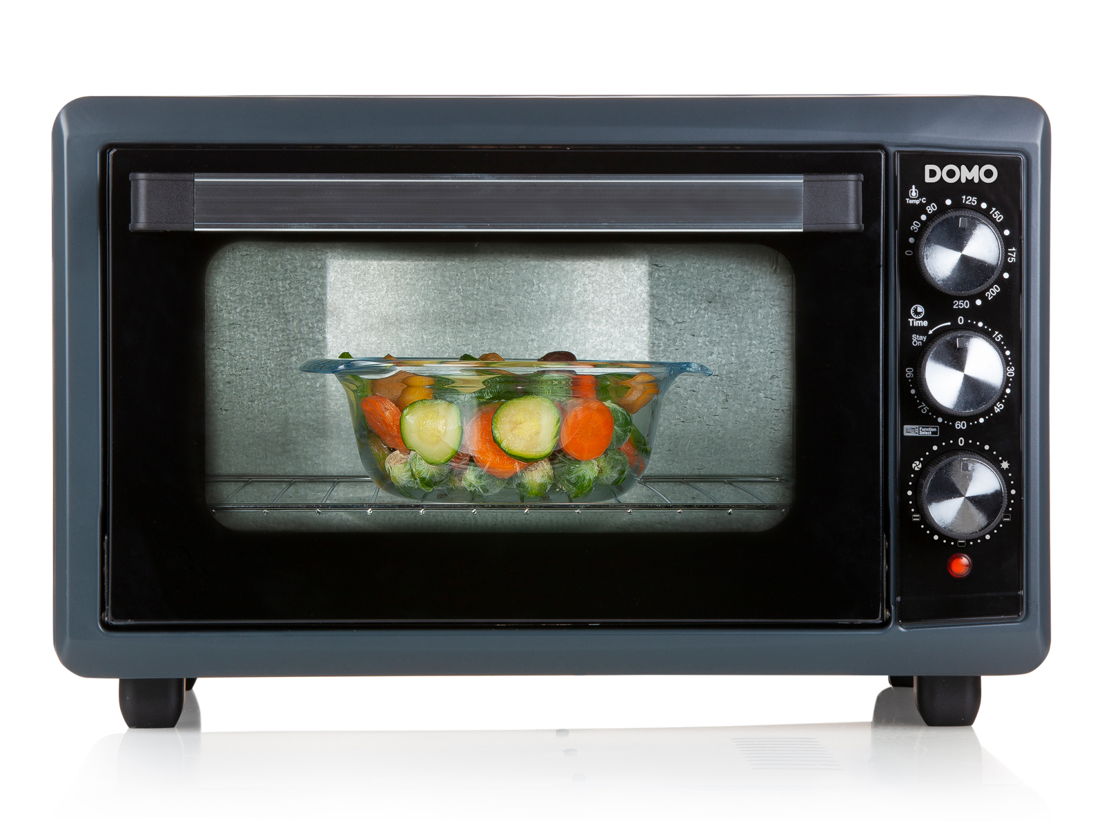 Szary piekarnik ze szklanymi drzwiami. Warzywa wewnątrz w szklanej misce.