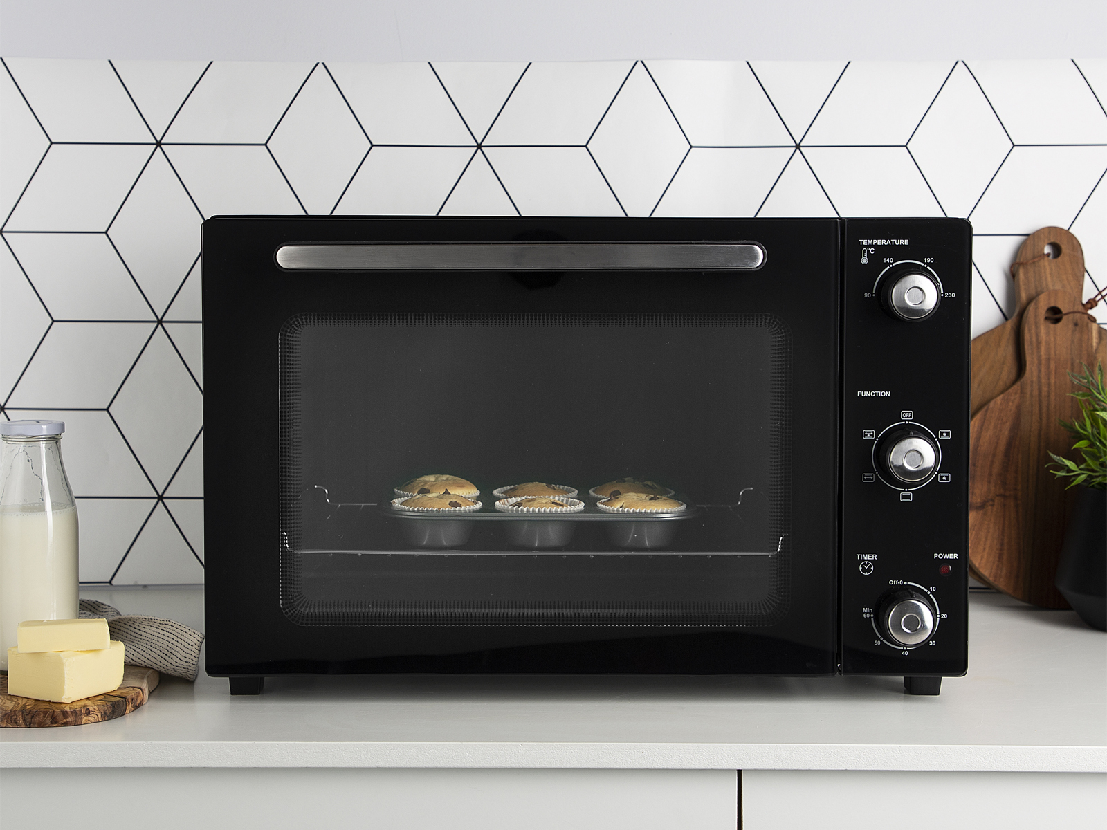 Un four noir sur un comptoir blanc. Il y a trois tartes à l'intérieur, avec des boutons à droite.