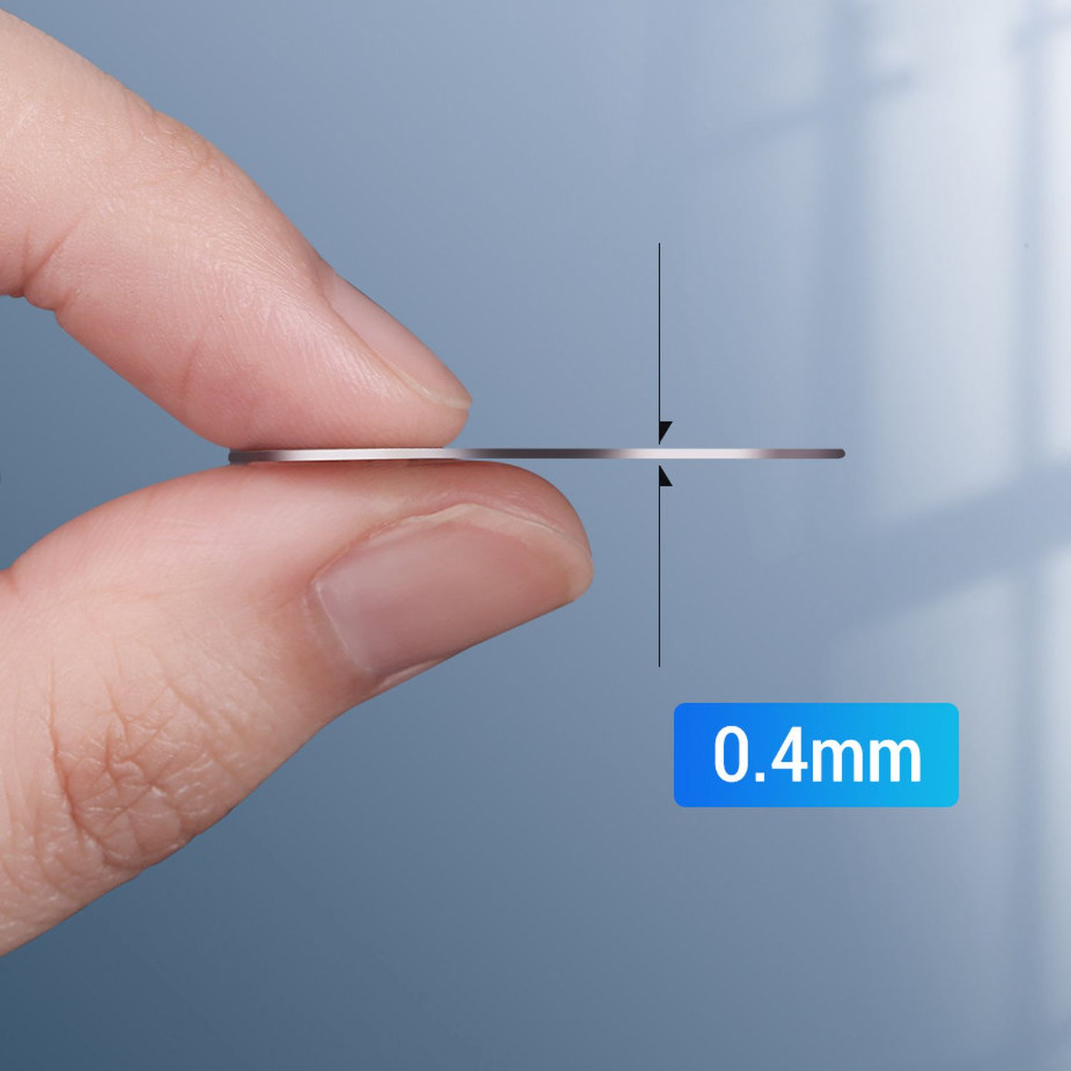 Nahaufnahme einer Hand, die eine sehr dünne, silberfarbene Scheibe hält. Dicke 0,4 mm.