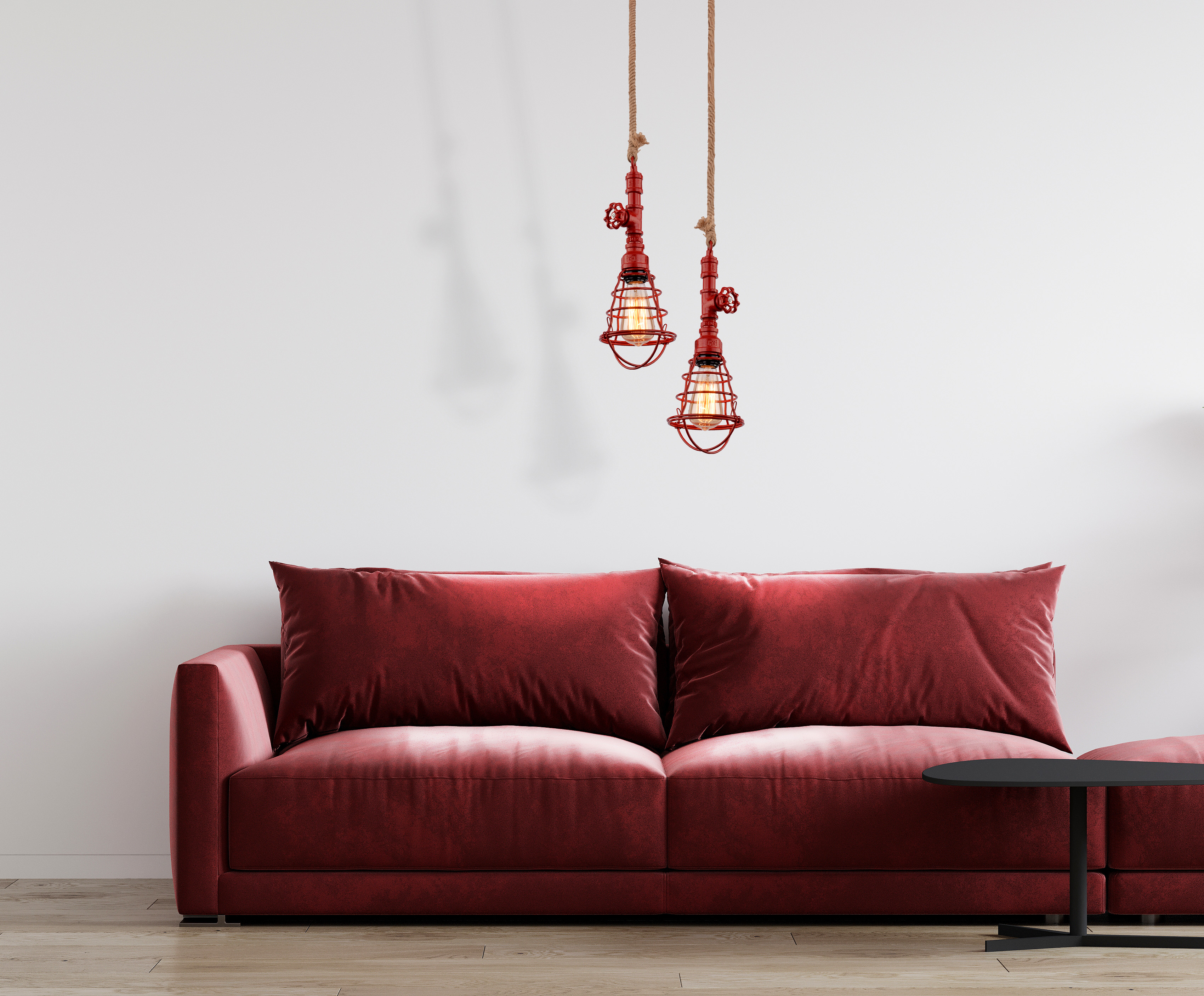 Wohnzimmerszene mit rotem Sofa, zwei roten Pendelleuchten und einem schwarzen Beistelltisch. Weiße Wände.