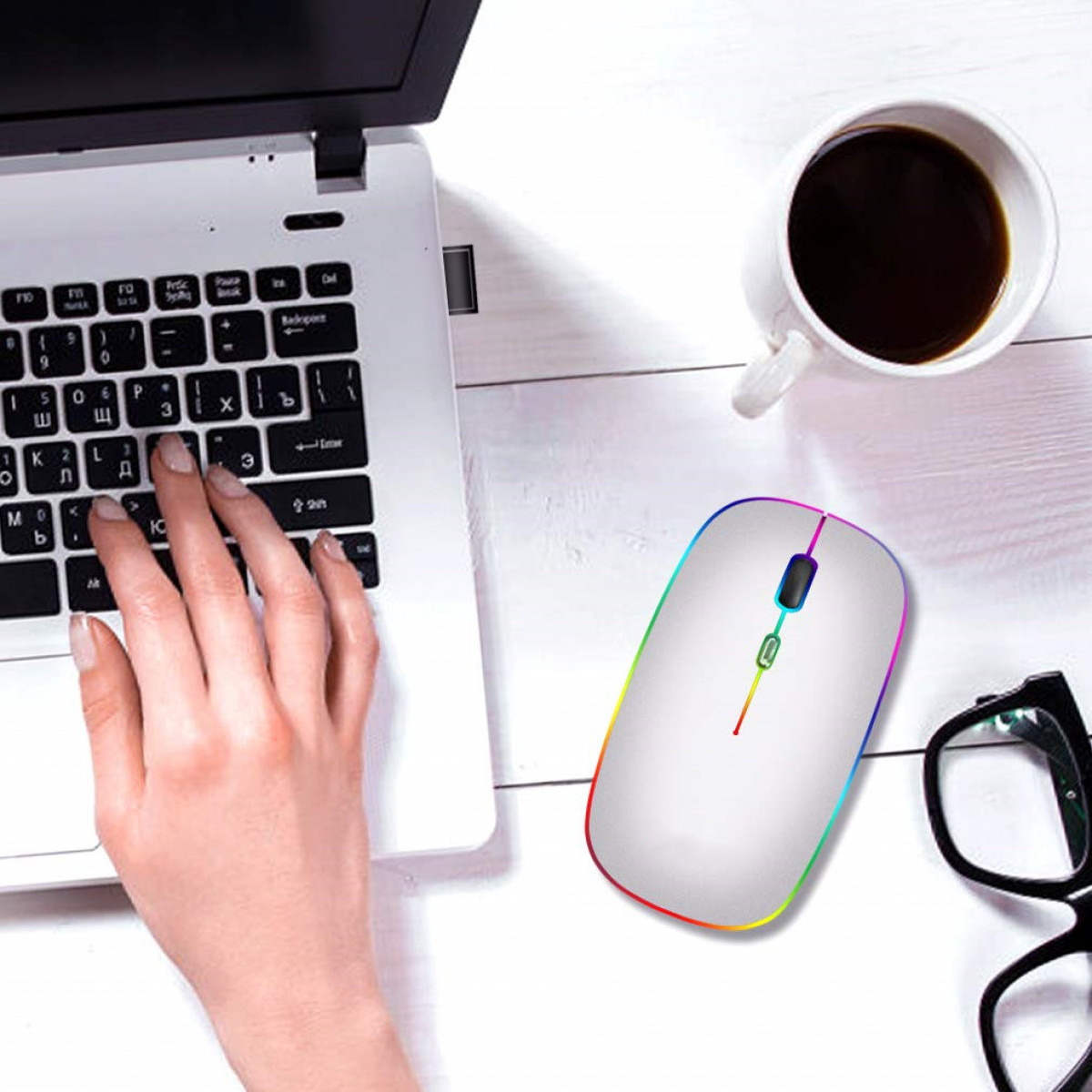 Eine Person benutzt eine weiße kabellose Maus. Laptop und Kaffeetasse befinden sich ebenfalls auf der weißen Oberfläche.