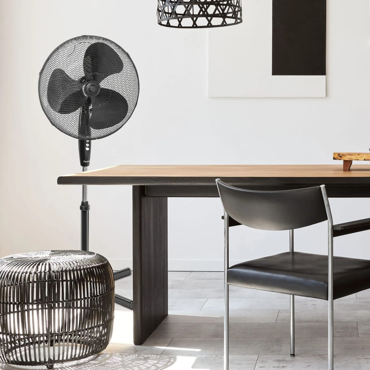 Czarny wentylator na stojaku w pokoju ze stołem i krzesłem.