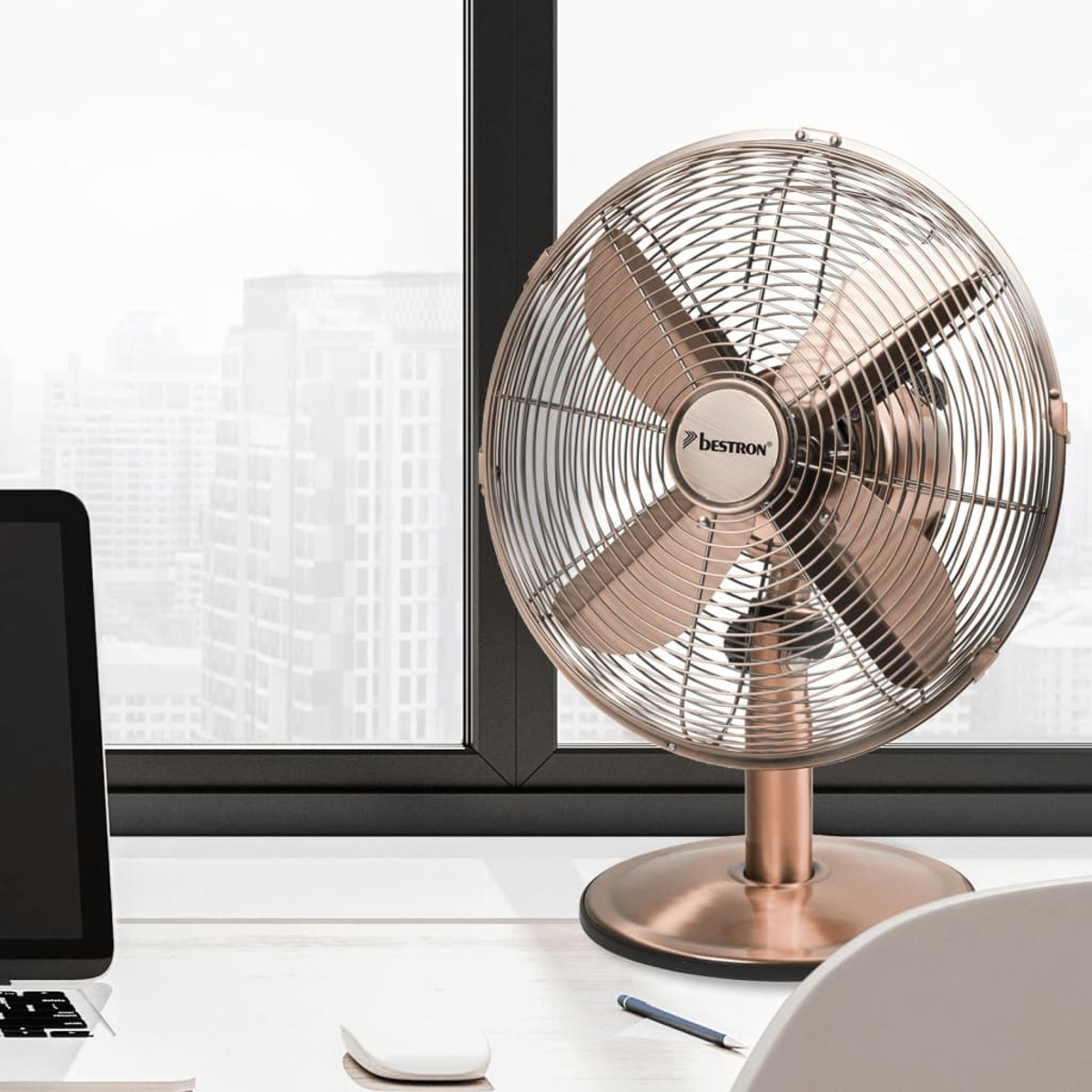 Un ventilatore in bronzo su una scrivania, un laptop e un mouse sono visibili.
