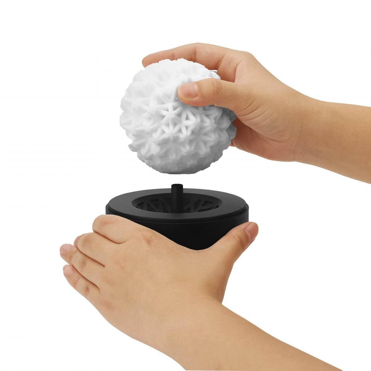 Hände, die einen weißen, stacheligen Ball in eine schwarze, kreisförmige Basis auf weißem Hintergrund zusammensetzen.