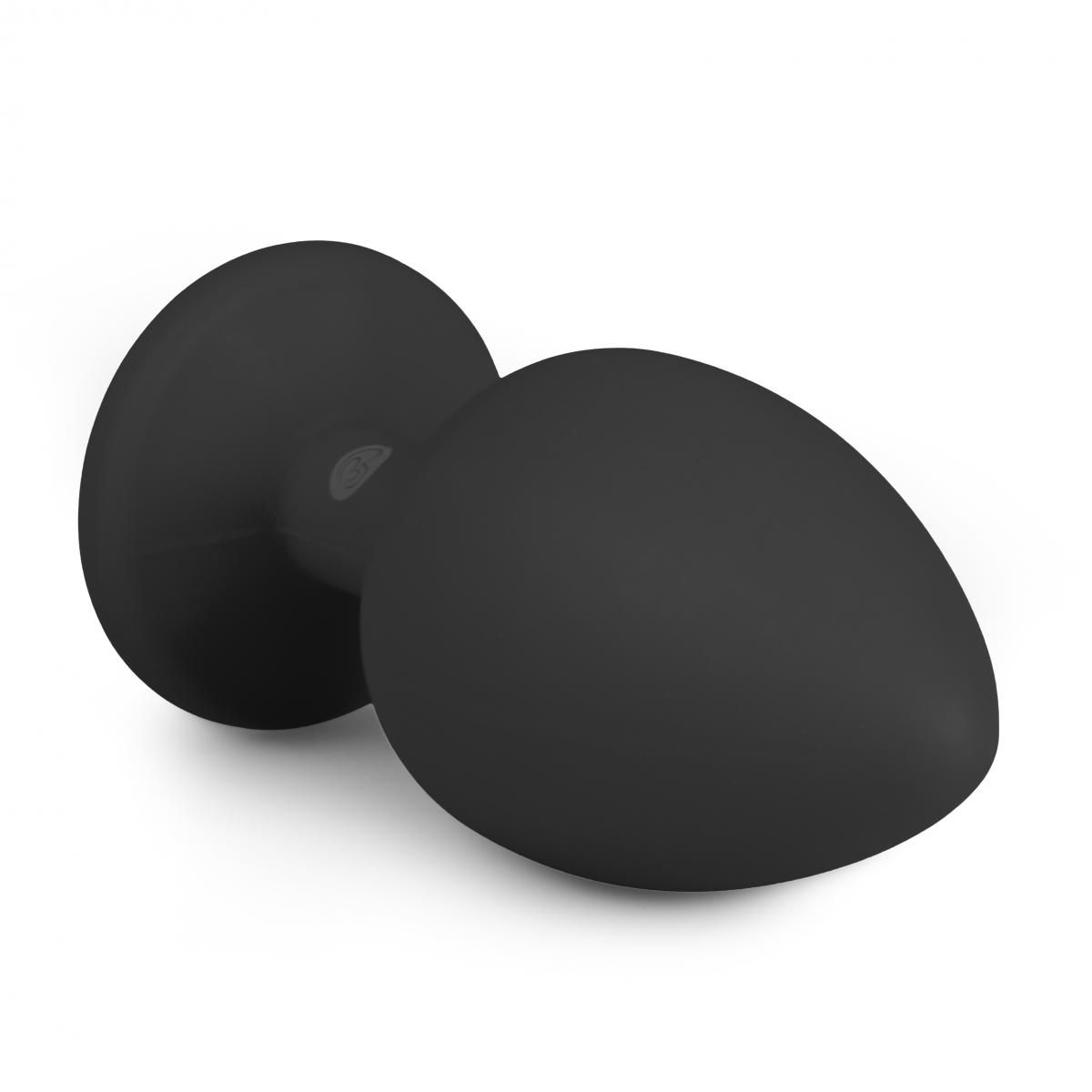 Ein schwarzes, glattes, tropfenförmiges Objekt mit ausgestellter Basis. Es ist wahrscheinlich ein Sexspielzeug, vor weißem Hintergrund.