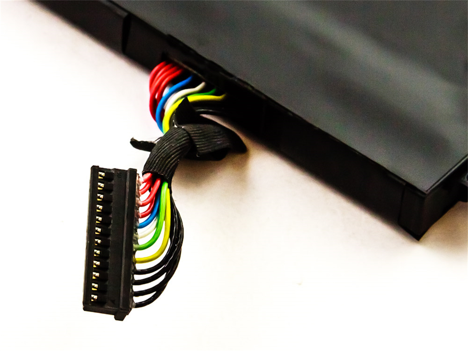 Eine schwarze elektronische Komponente mit bunten Drähten und einem Stecker.