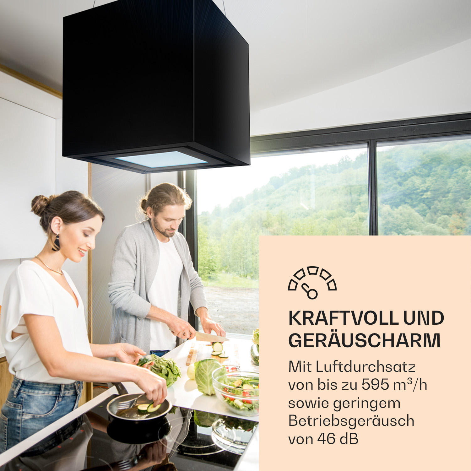 Ein Paar kocht in einer Küche mit einer schwarzen Dunstabzugshaube über ihnen.