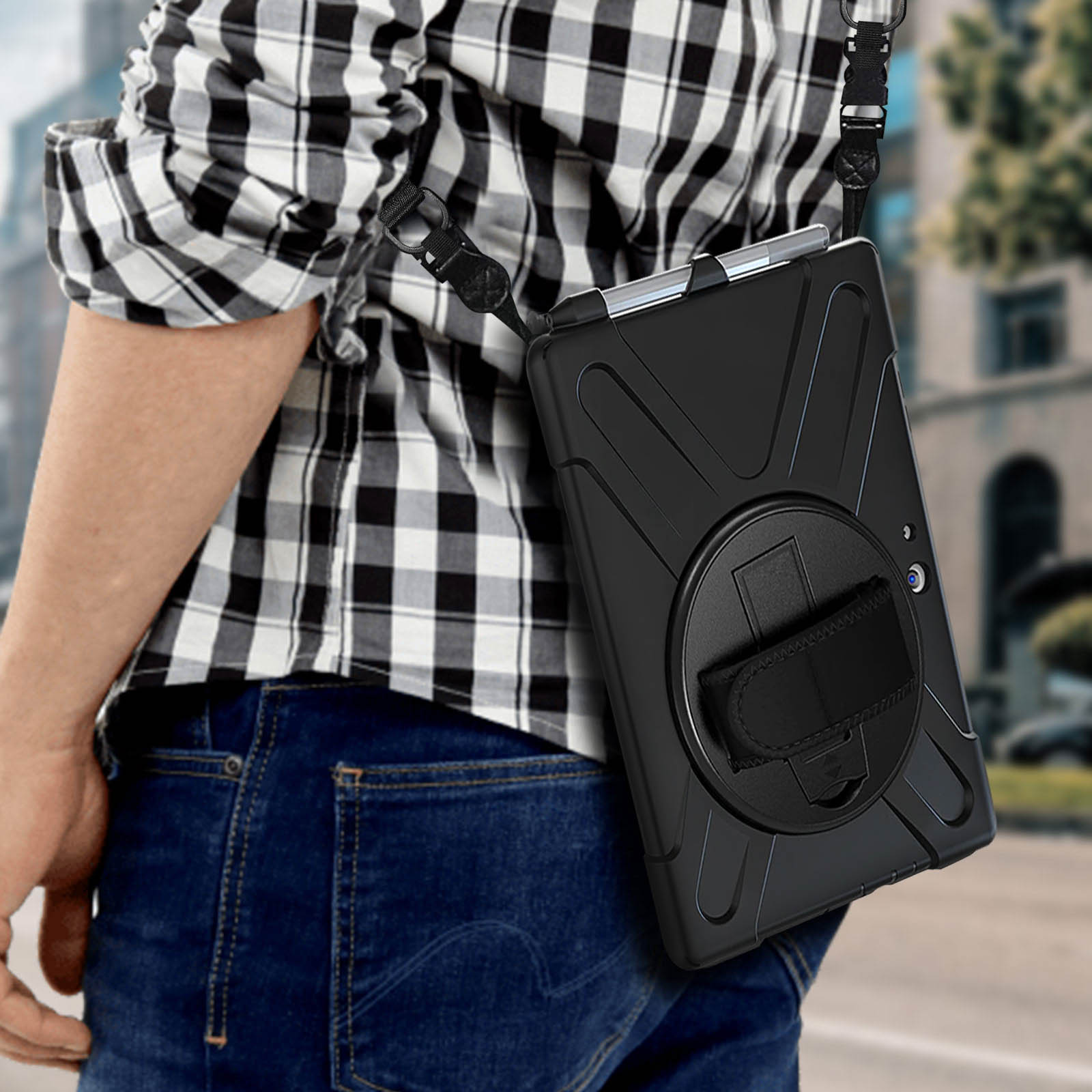 Eine Person, die eine schwarze Tablet-Hülle mit Riemen trägt, geht auf einer Stadtstraße.