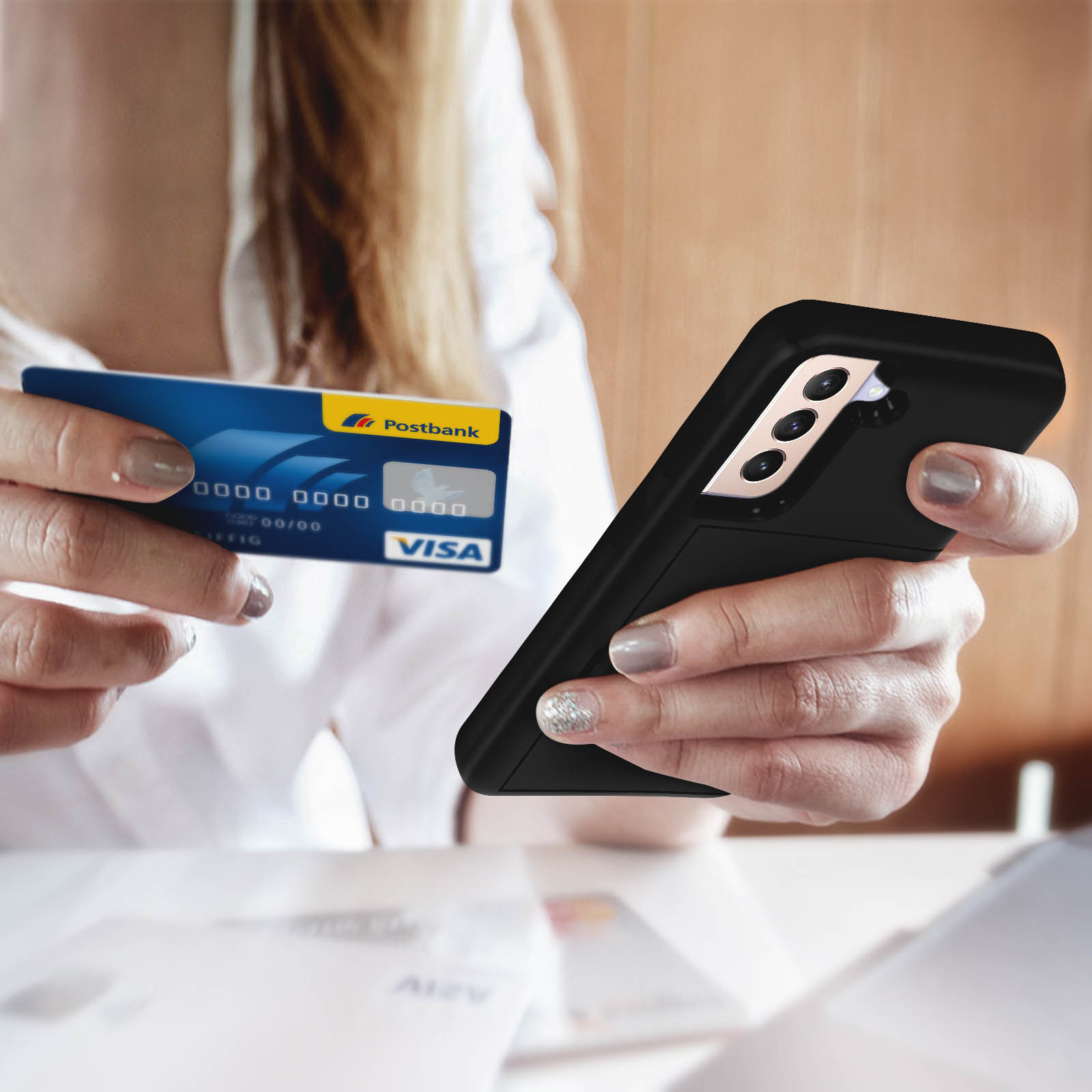 Una persona tiene in mano una custodia per telefono e una carta di credito. La custodia è nera e la carta blu.