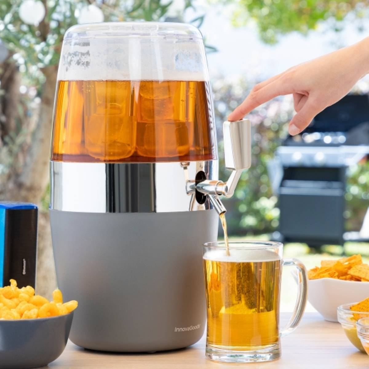 Un distributore di birra eroga birra in una tazza. Snack e un grill sullo sfondo.