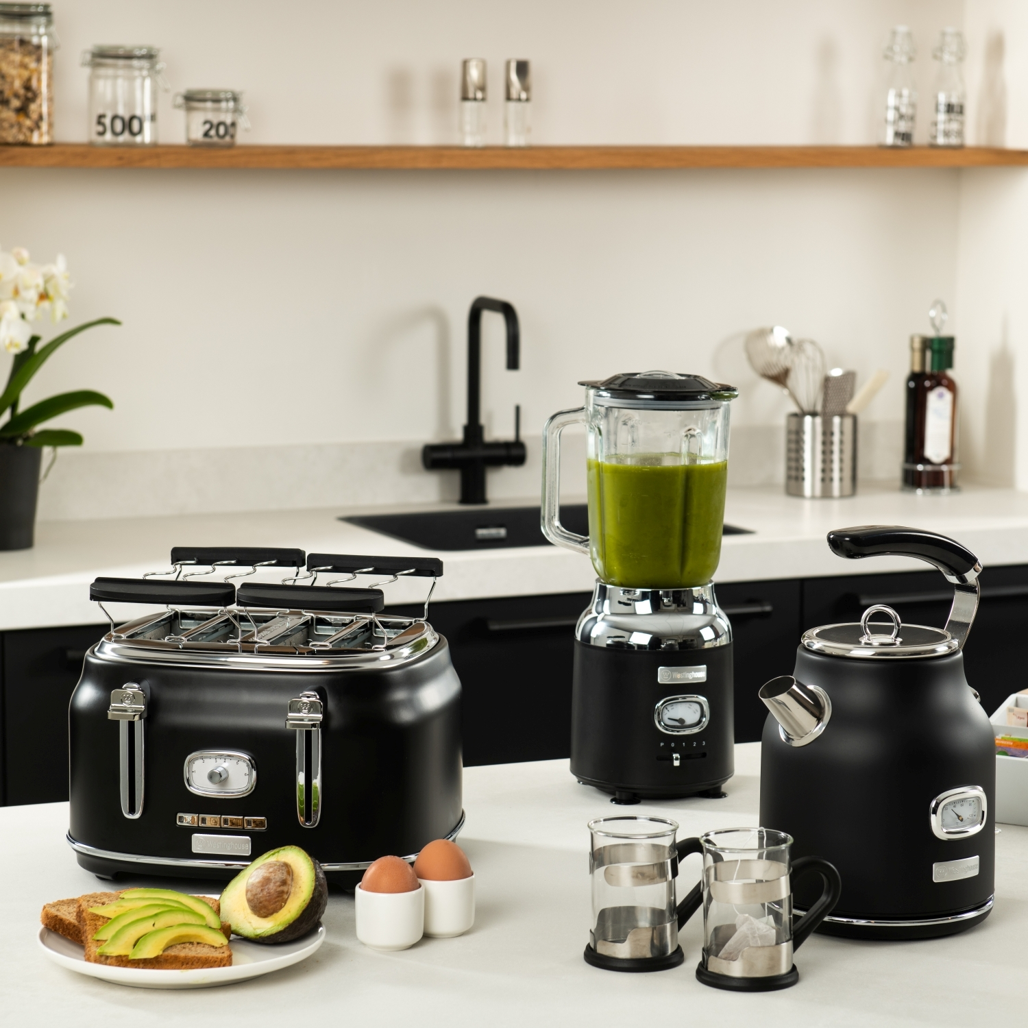 Küchentheke mit Geräten und Lebensmitteln. Enthält Toaster, Mixer, Wasserkocher, Avocado und Eier.