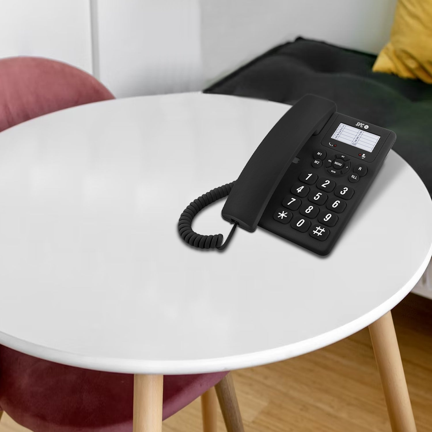 Teléfono fijo negro sobre una mesa blanca. Mesa pequeña con patas de madera.