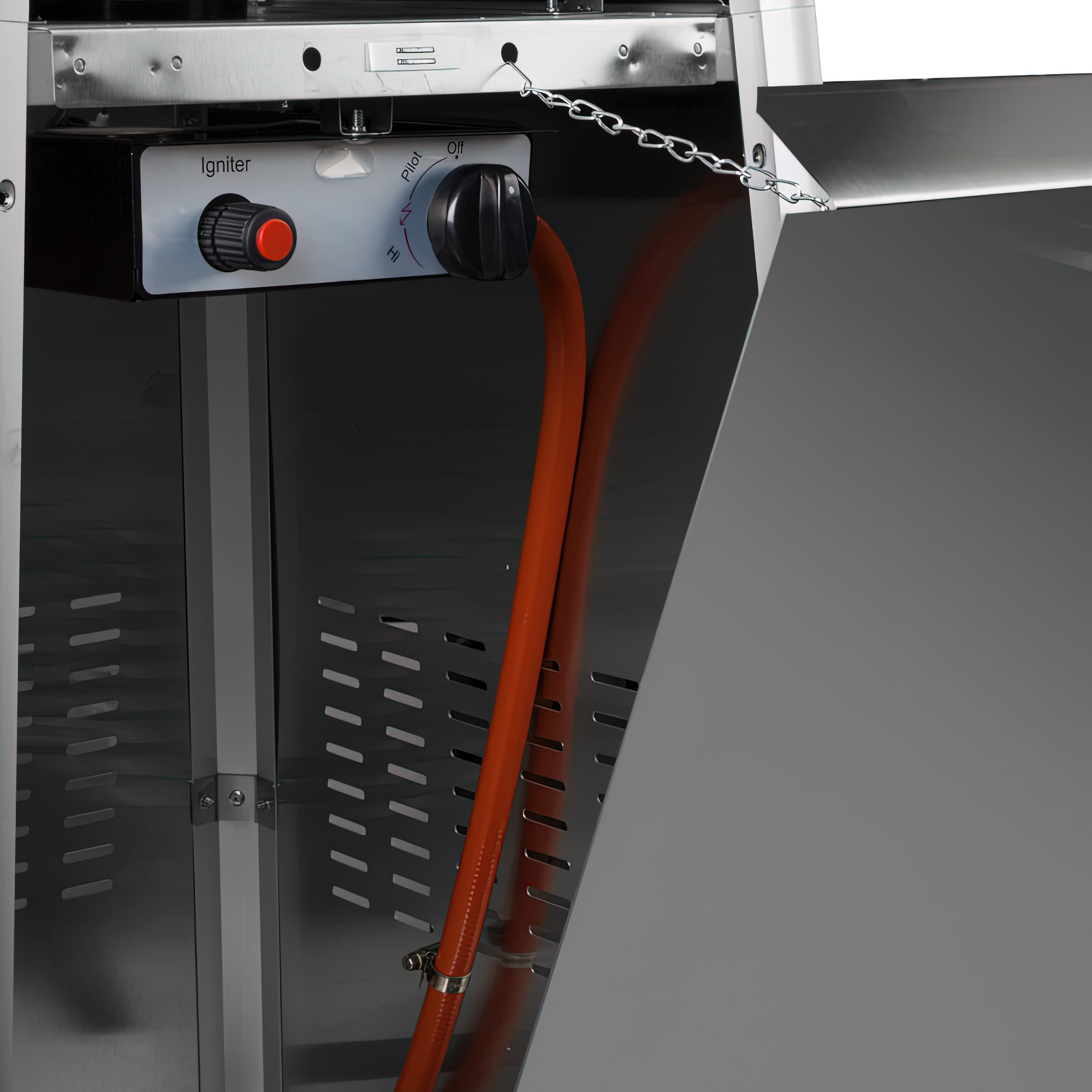 Primer plano del panel de control de una parrilla. Botón de encendido rojo, perillas negras y línea de gas naranja.