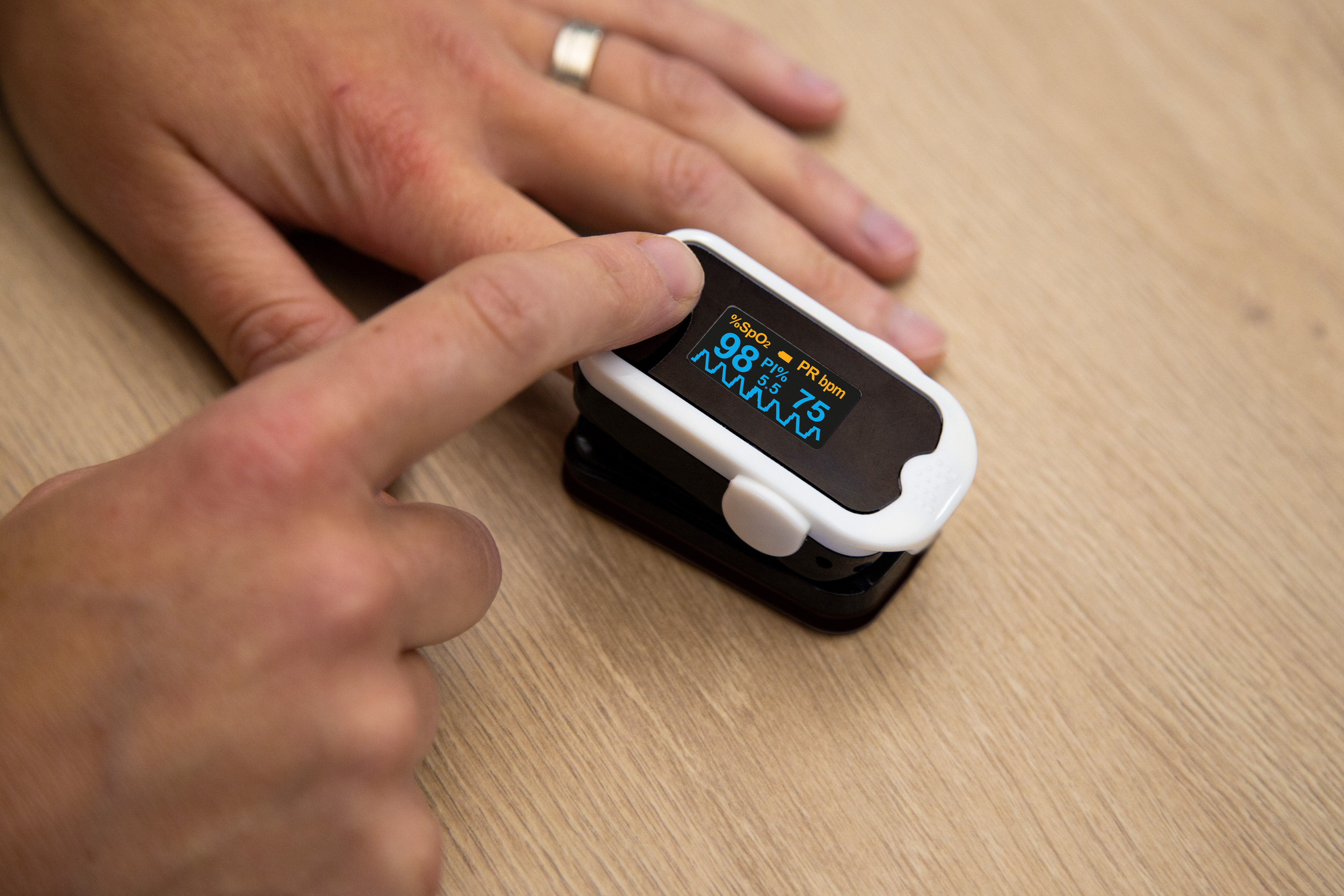 Der Finger einer Person auf einem Pulsoximeter, das die Sauerstoffsättigung misst.
