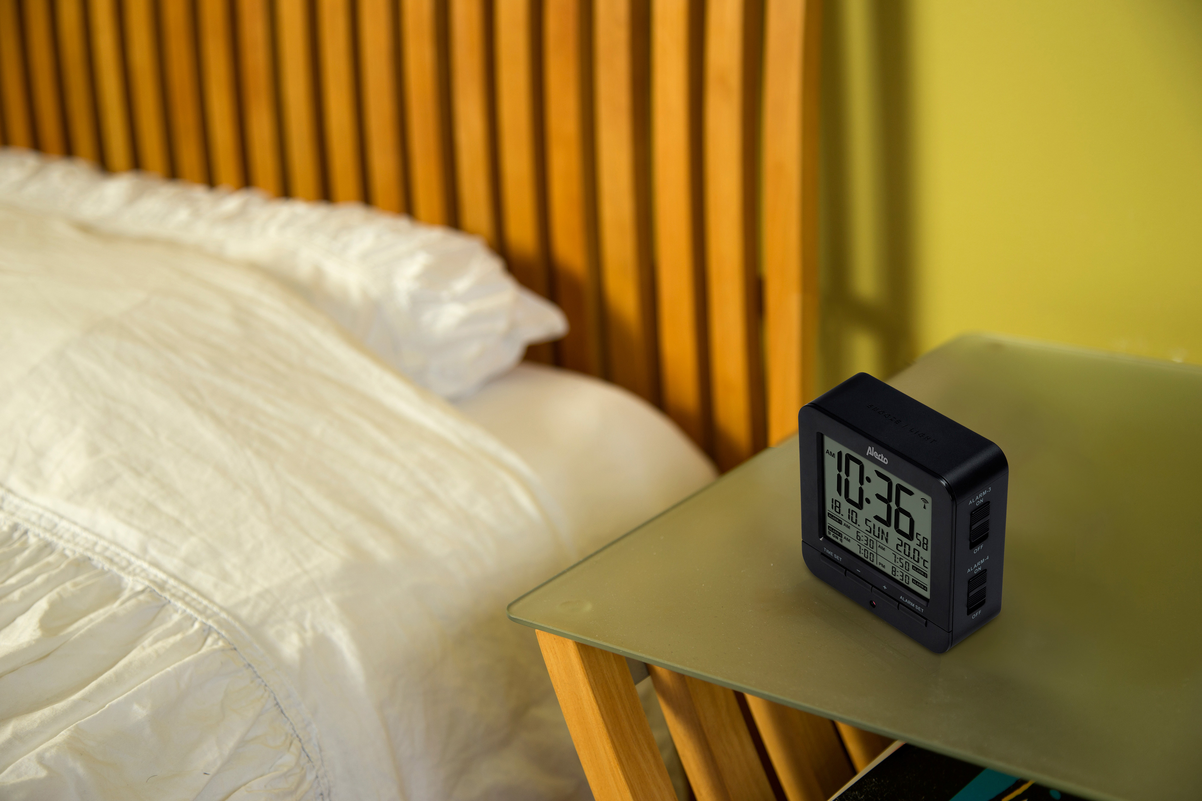 Slaapkamerscène met een bed en een nachtkastje. Zwarte klok op de tafel, die 10:36 aangeeft.