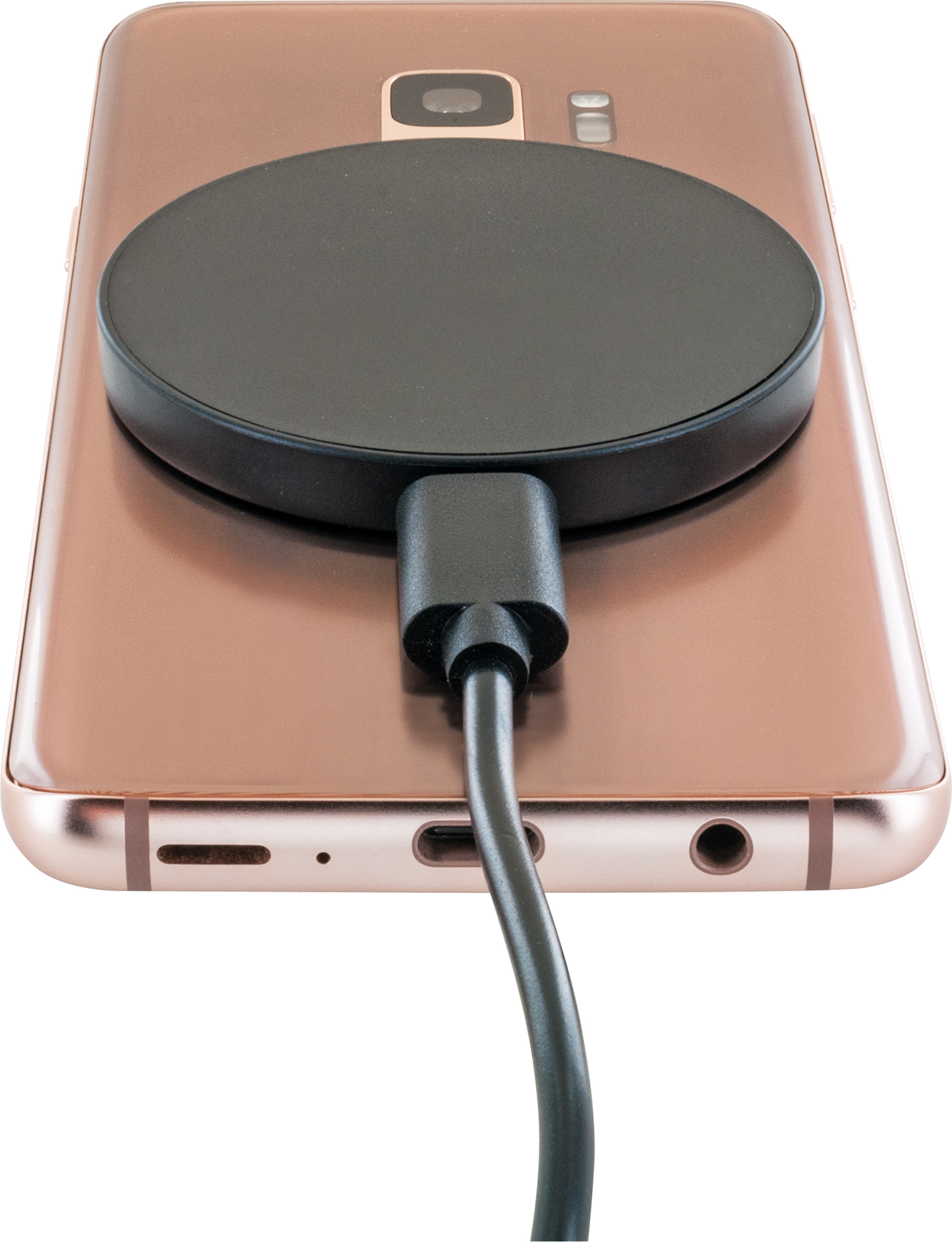 Die Rückseite eines roségoldenen Telefons mit einem angeschlossenen schwarzen Ladepad.