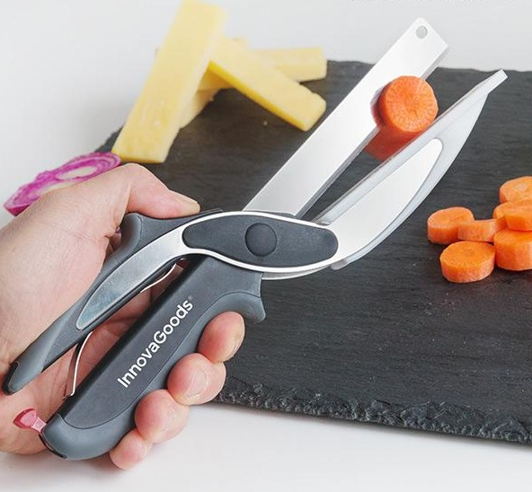Hand hält scherenartiges Küchenwerkzeug beim Schneiden von Karotten und Käse.