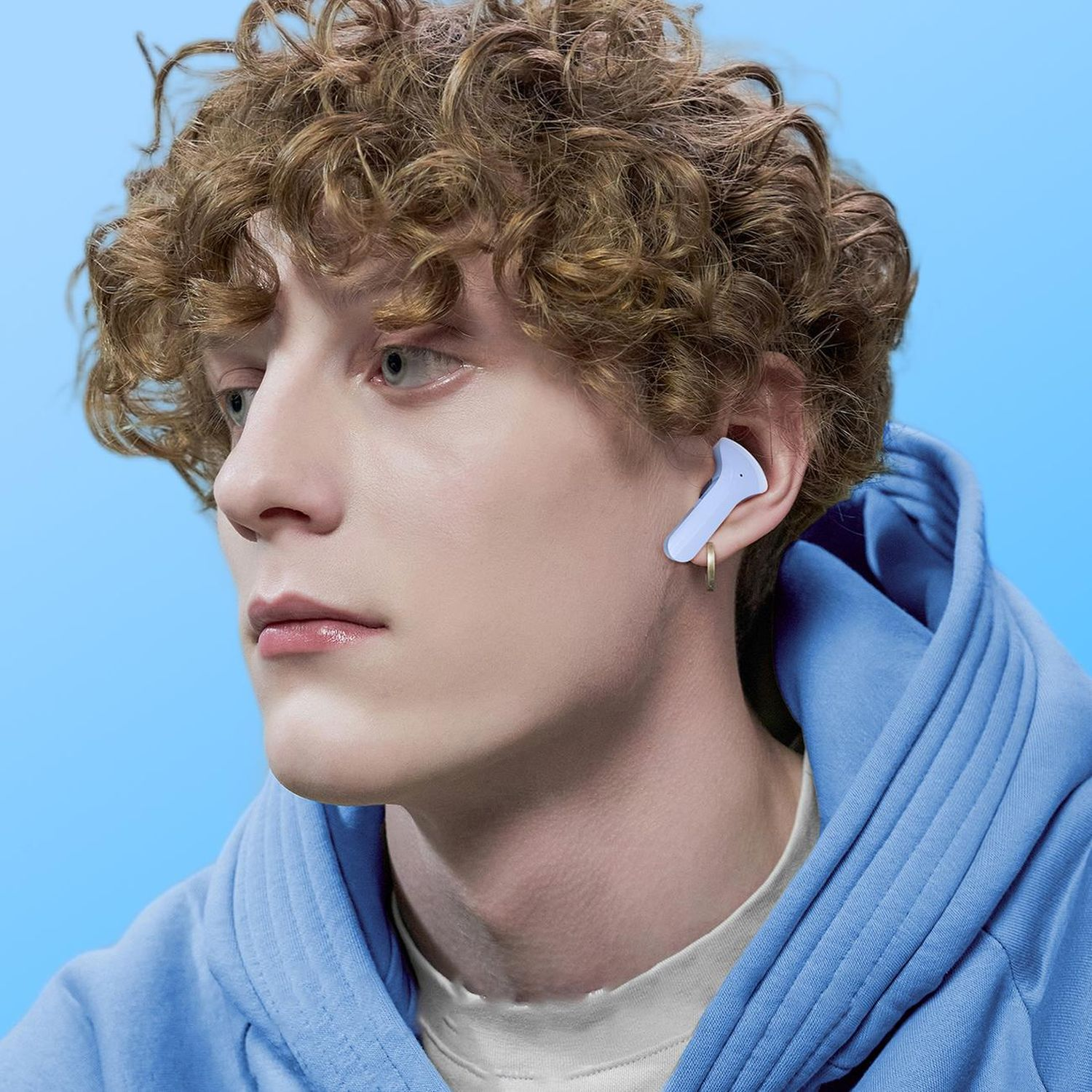 Ein Mann mit blauem Hoodie hat einen hellblauen Ohrhörer im Ohr.