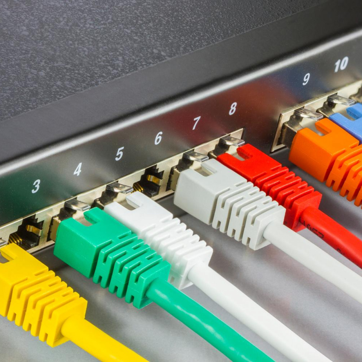 Ein Netzwerk-Switch mit mehreren farbigen Ethernet-Kabeln, die eingesteckt sind, nummerierte Ports.