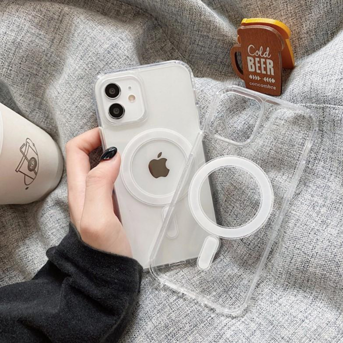 Hand hält Telefon in transparenter Hülle, mit MagSafe-Ring und Bierdeckel.