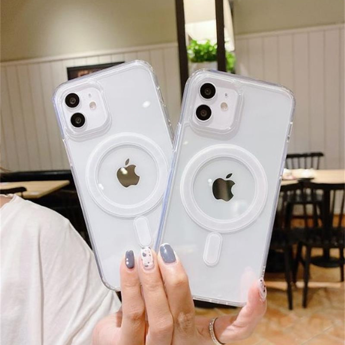 Zwei weiße Handyhüllen mit Apple-Logo-Ausschnitt und weißem Ring auf der Rückseite, gehalten von einer Hand.