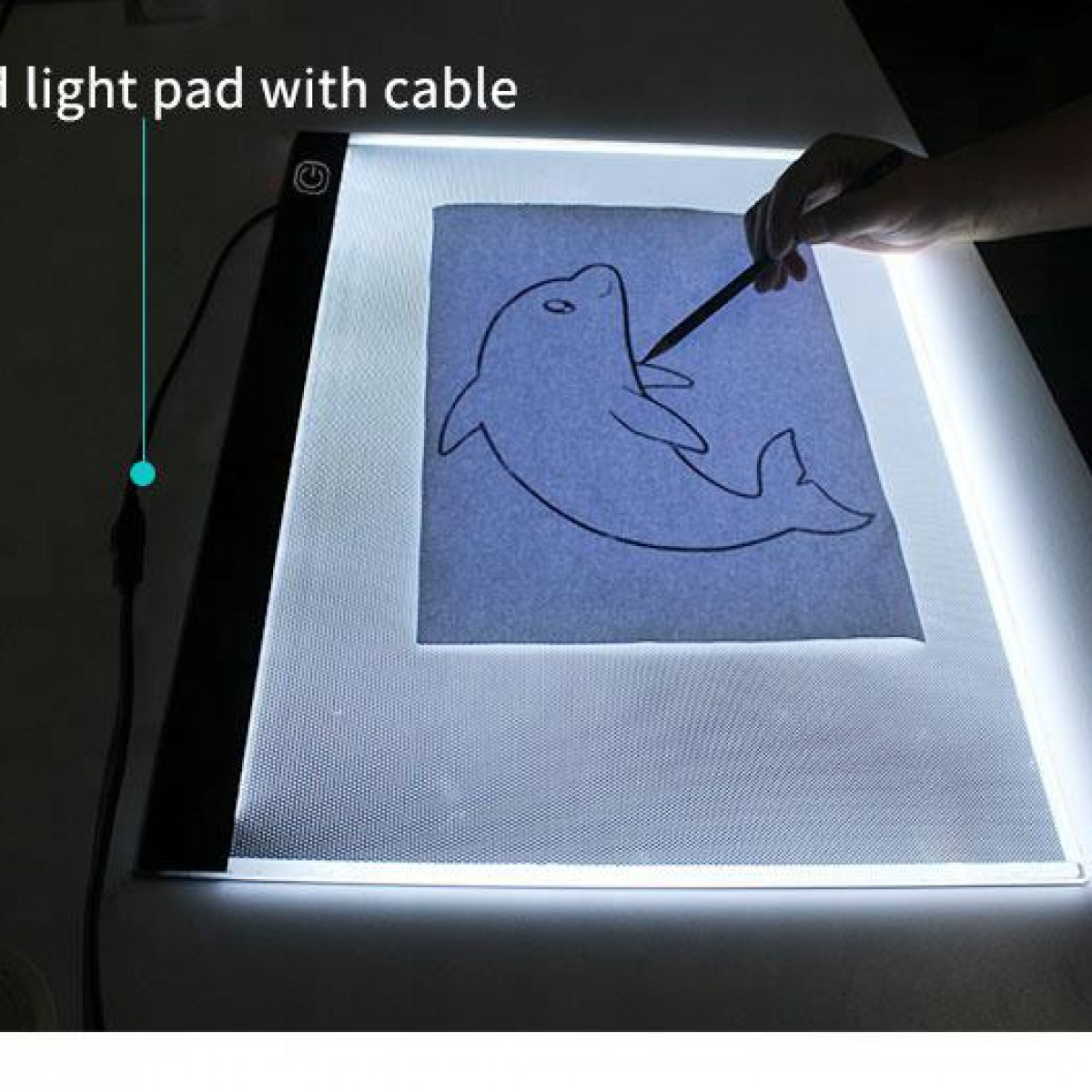 Una almohadilla de luz con un dibujo de delfín, una mano sosteniendo un bolígrafo y un cable.