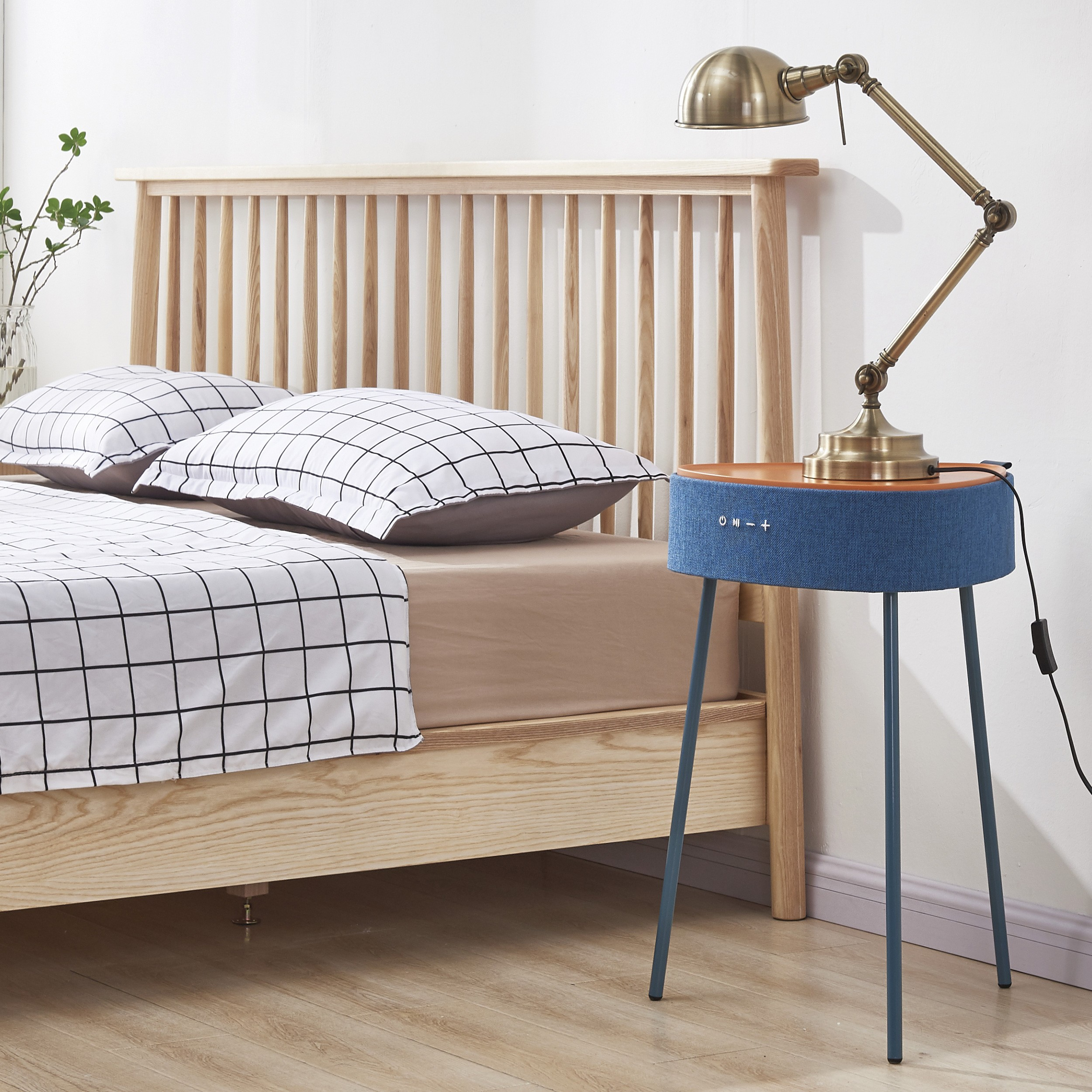 Escena de dormitorio con cama, almohadas y mesa auxiliar con lámpara.