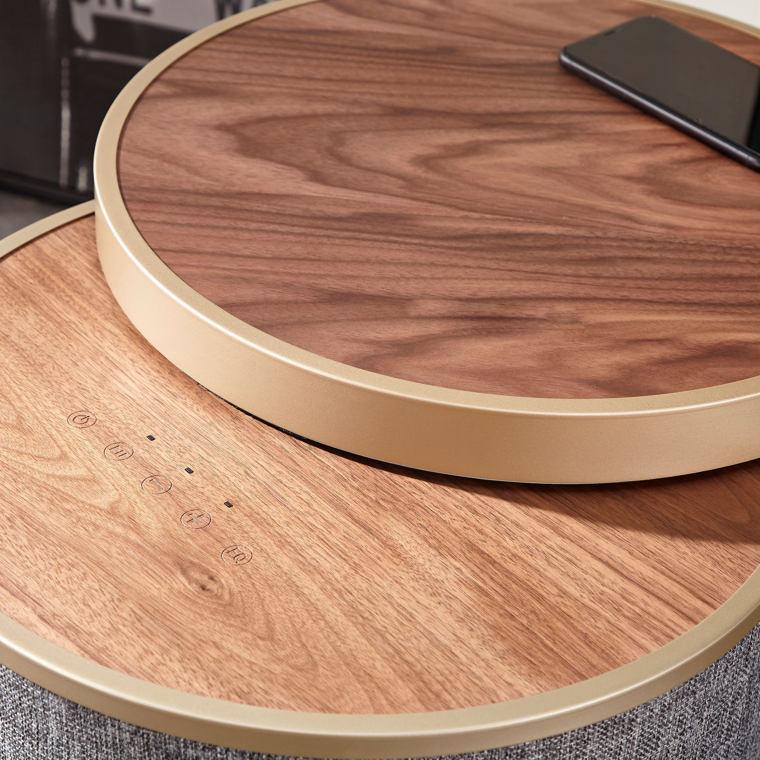 Dos mesas redondas de madera, una encima de la otra. Un smartphone está sobre la mesa superior.