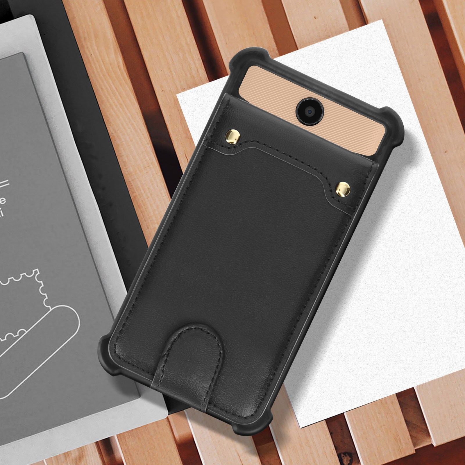 Una custodia per telefono nera con un telefono e una carta all'interno. La custodia è su uno sfondo di legno.