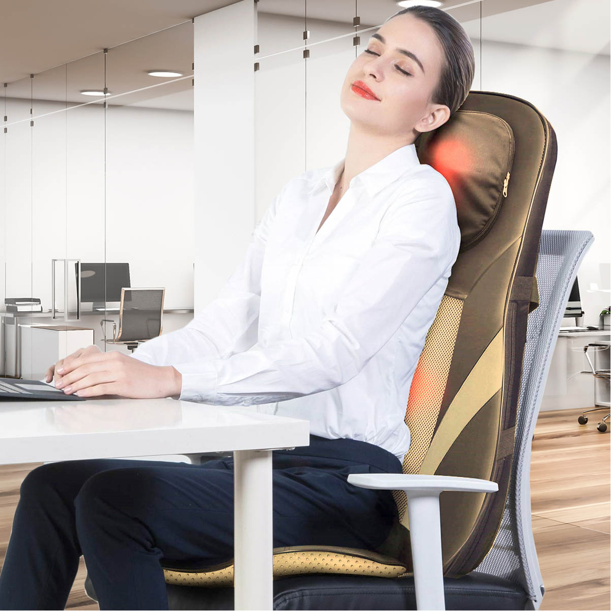 Mujer con camisa blanca sentada en un escritorio, usando una silla de masaje con función de calor rojo.
