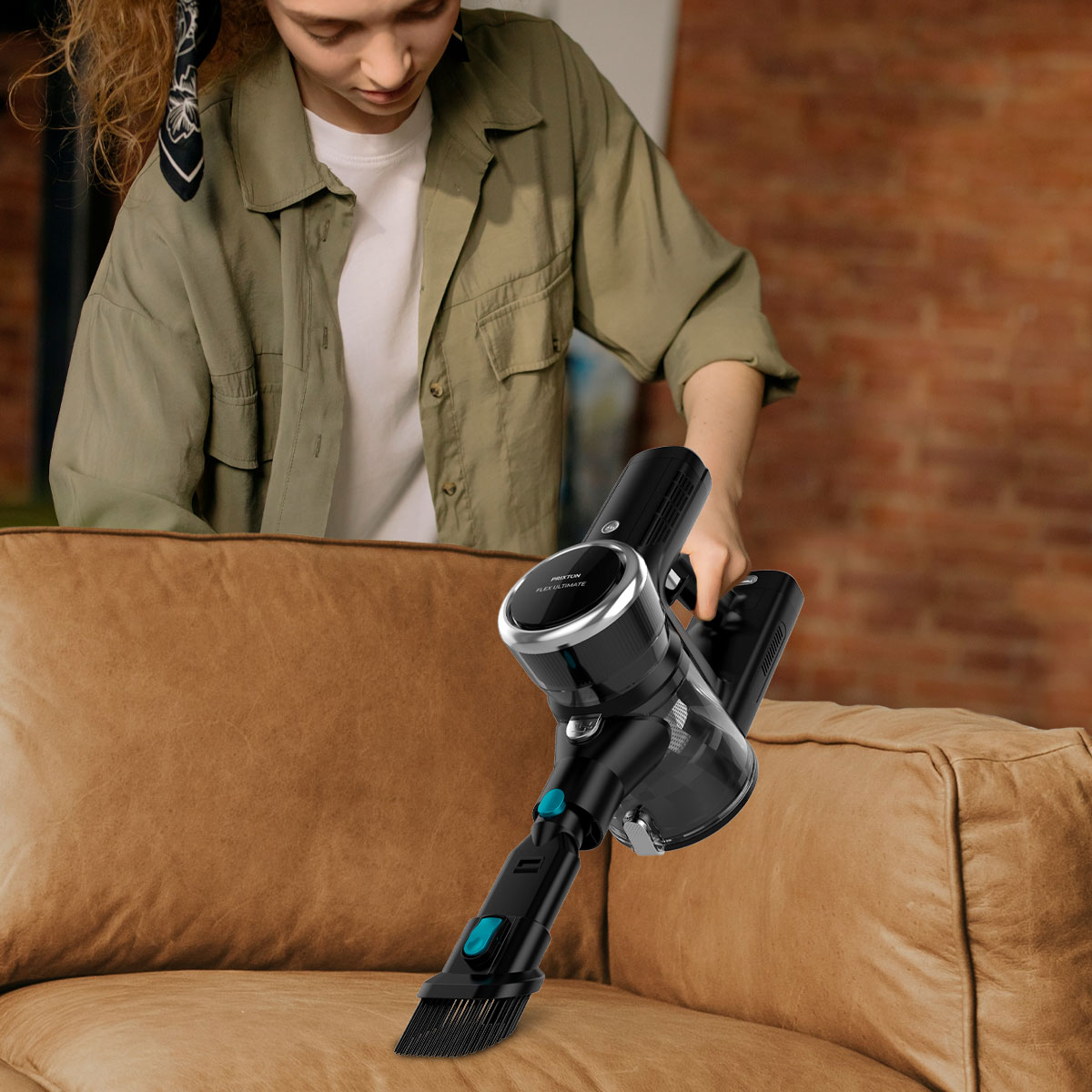 Kobieta używa czarno-srebrnego odkurzacza na brązowej kanapie.