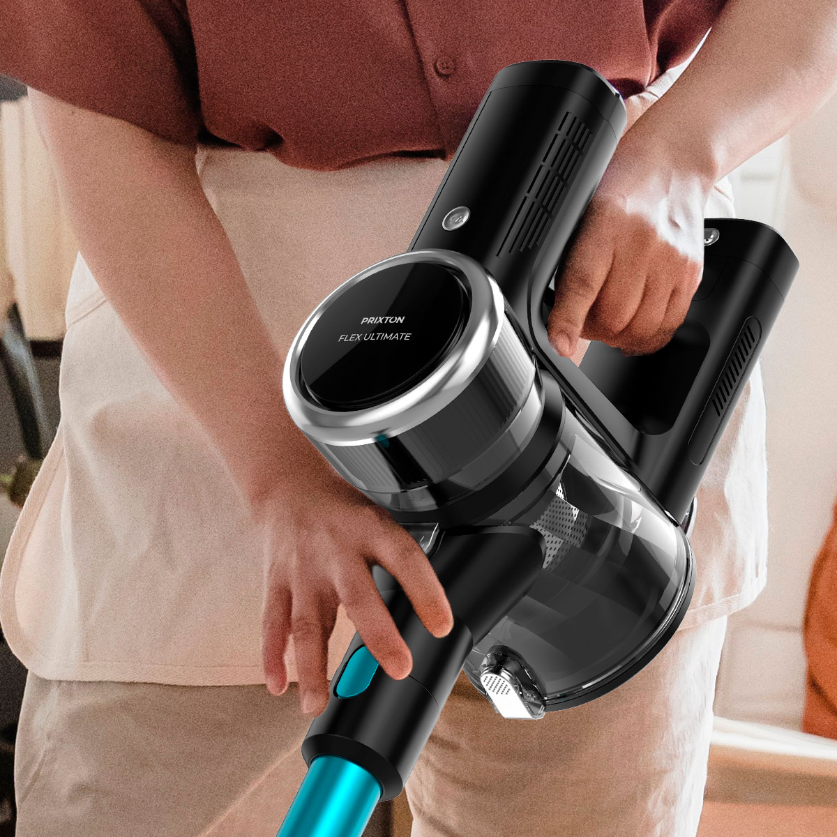 Osoba trzymająca czarno-srebrny odkurzacz bezprzewodowy z niebieskim detalem, w pobliżu białego fartucha.