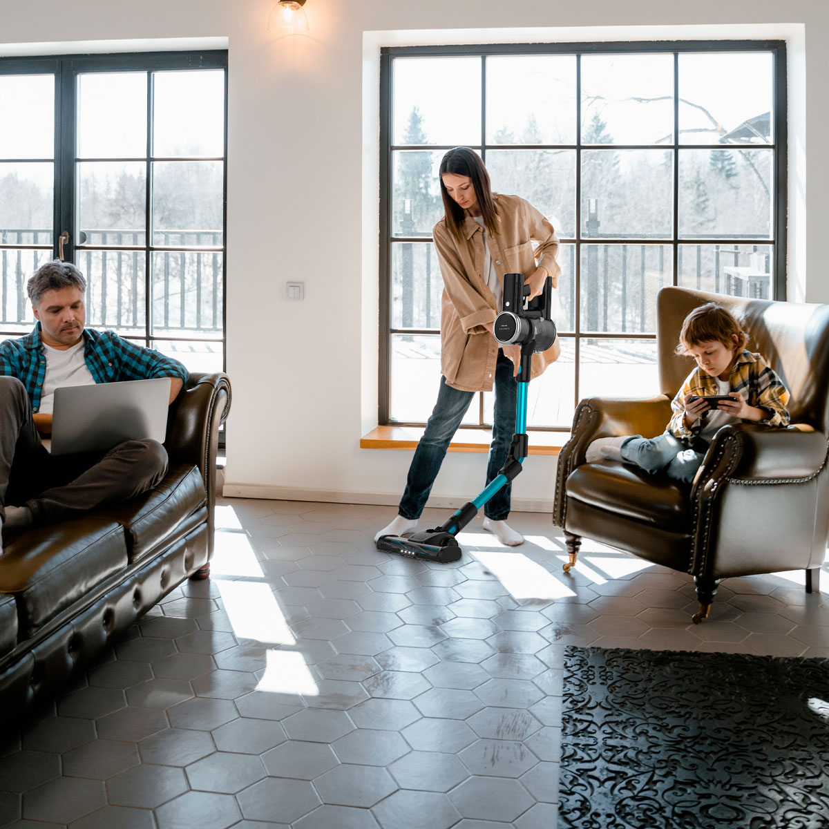 Rodzina w salonie. Kobieta odkurza, mężczyzna na laptopie, dziecko gra w gry.