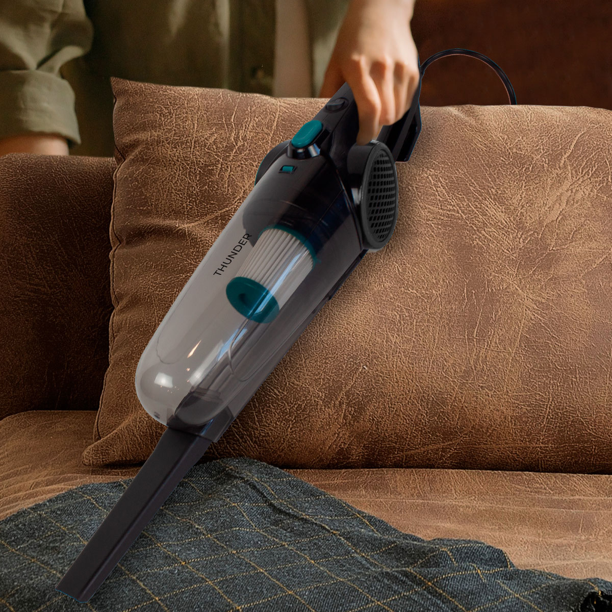 Odkurzacz ręczny w użyciu na sofie, trzymany przez osobę.