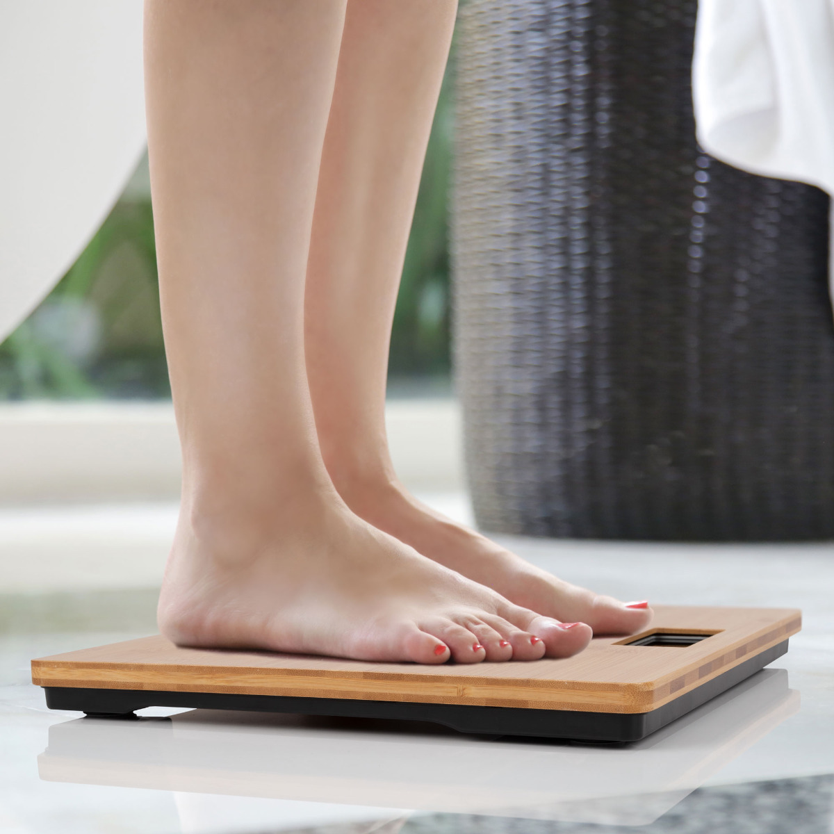 Bose stopy na drewnianej wadze. Waga jest czarna z cyfrowym wyświetlaczem. Scena łazienkowa.