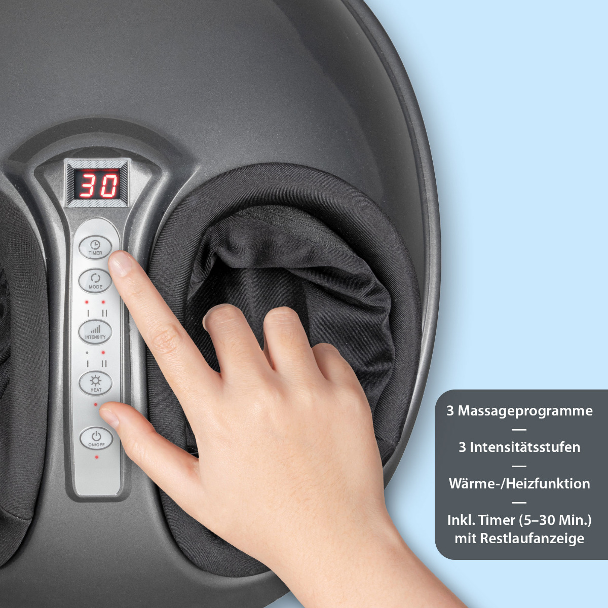 Ręka osoby używająca masażera stóp. Widoczne są przyciski na masażerze, a także tekst o funkcjach.