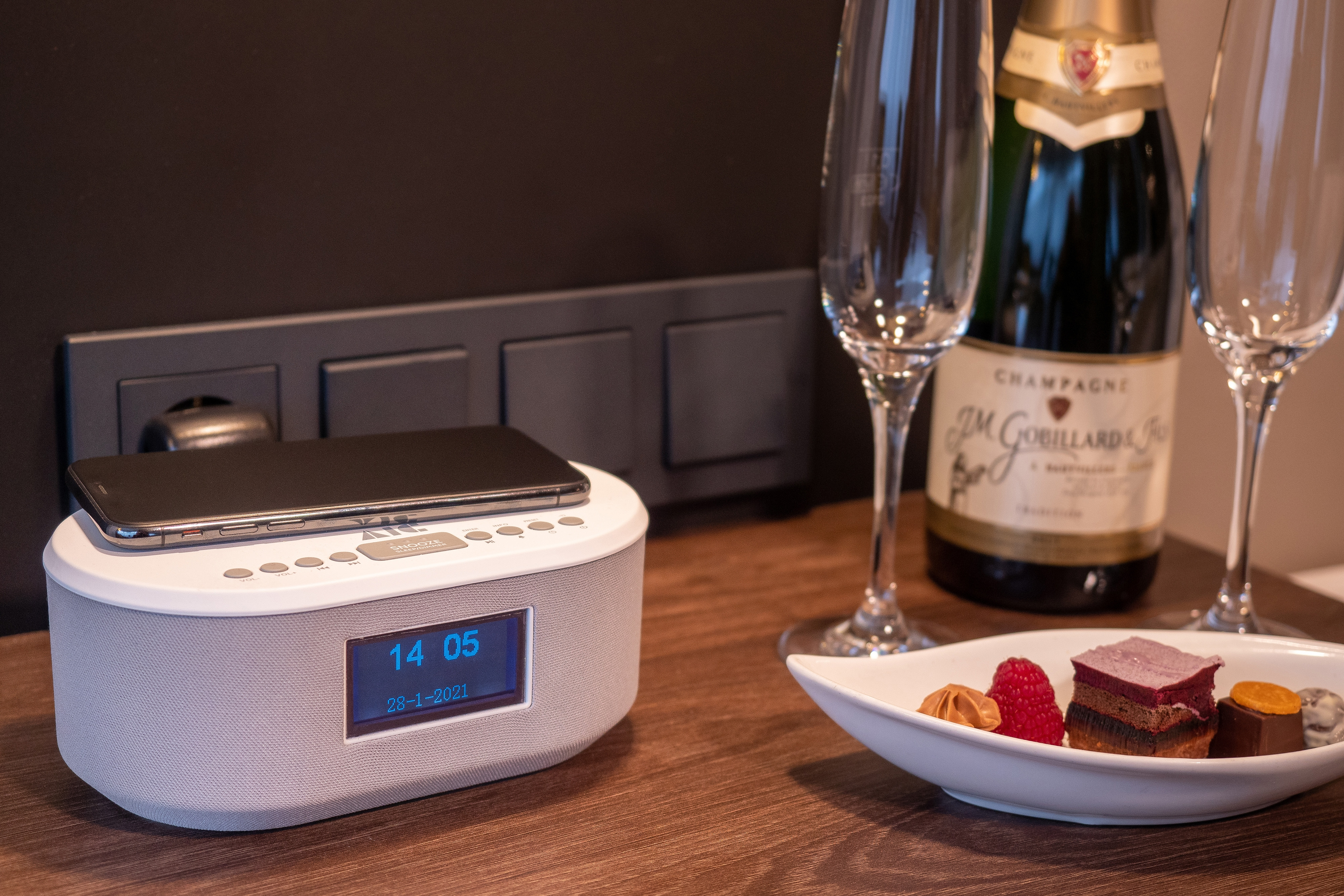 Schlafzimmer mit Champagnerflasche, Gläsern und einem Wecker mit Telefon oben drauf.