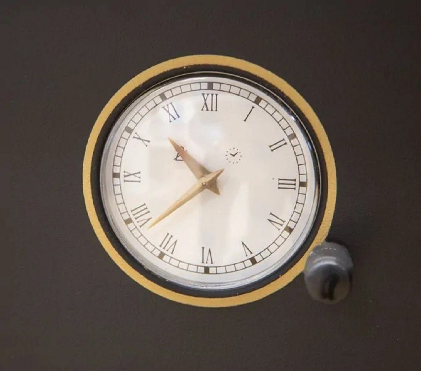 Nahaufnahme einer Uhr mit römischen Ziffern, in einem schwarz-goldenen Rahmen.