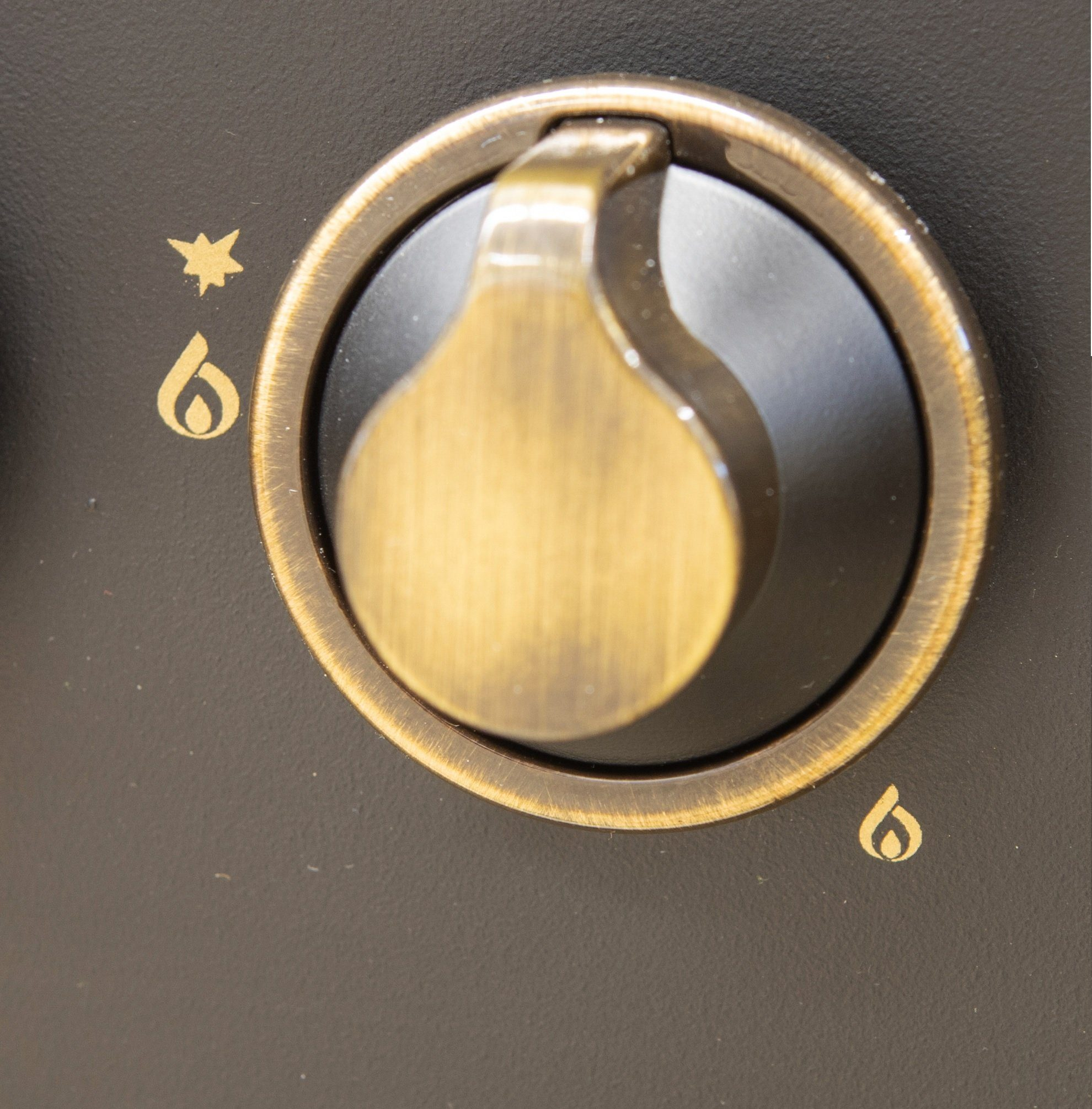 Nahaufnahme eines Ofenbedienknopfs mit Symbolen für einen Stern, eine Flamme und eine kleine Flamme.