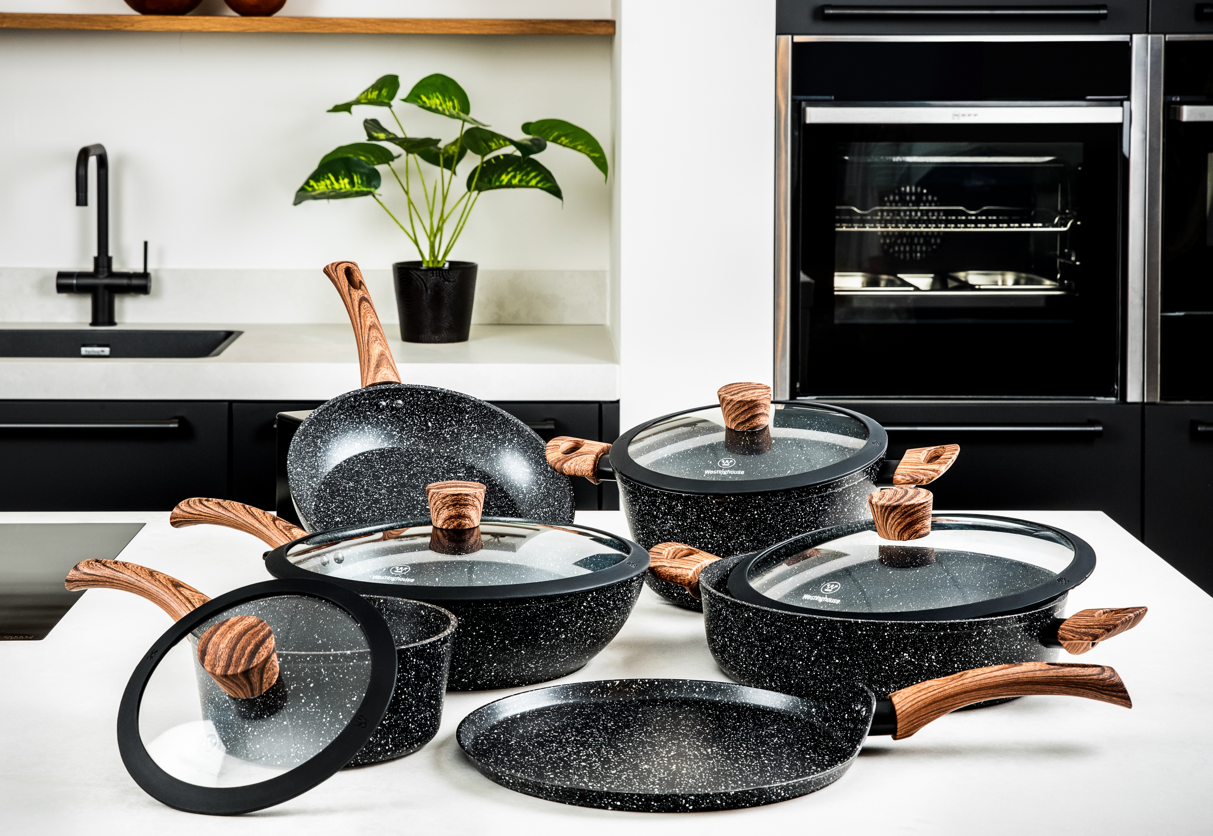 Küchenset aus Kochgeschirr mit gesprenkelter schwarz-grauer Oberfläche. Das Set enthält Töpfe, Pfannen und Deckel mit Holzgriffen.