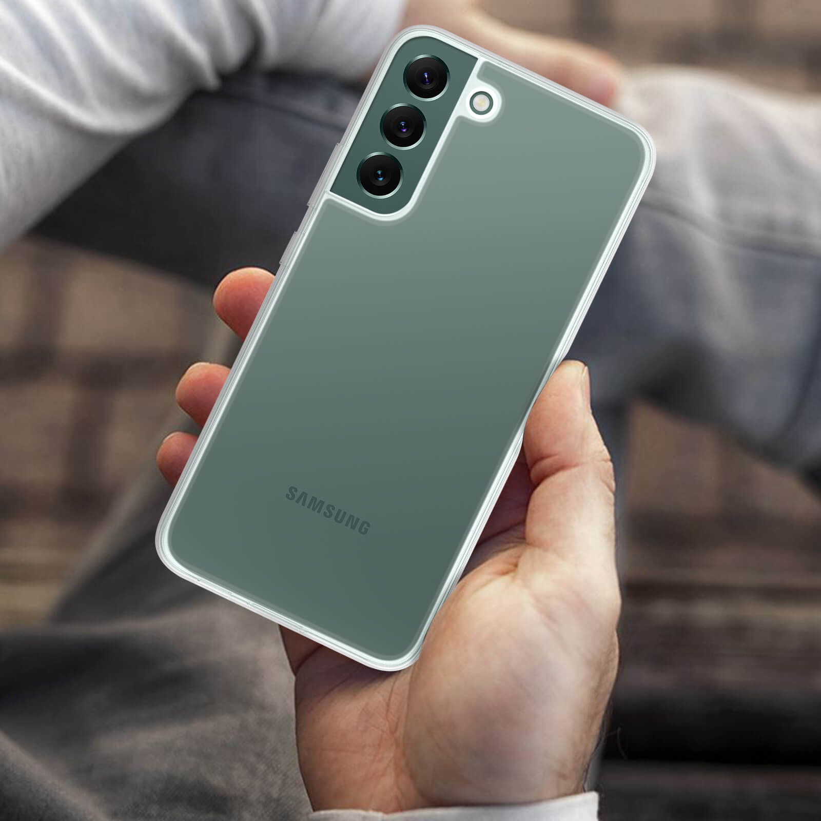 Mano che tiene un telefono verde con obiettivi della fotocamera. La custodia del telefono è trasparente.