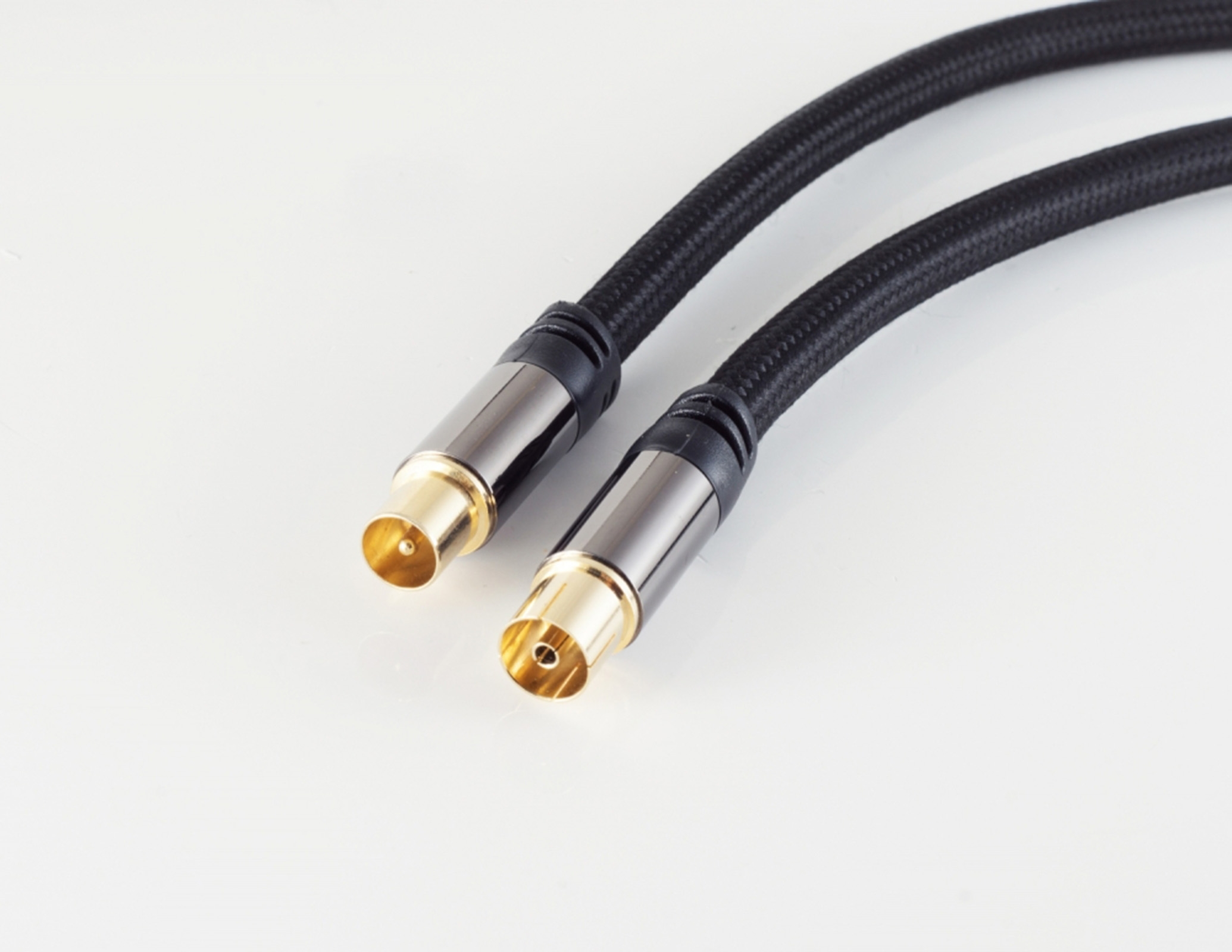 Zwei schwarze Audiokabel mit goldfarbenen Steckern auf weißer Oberfläche. Nahaufnahme.
