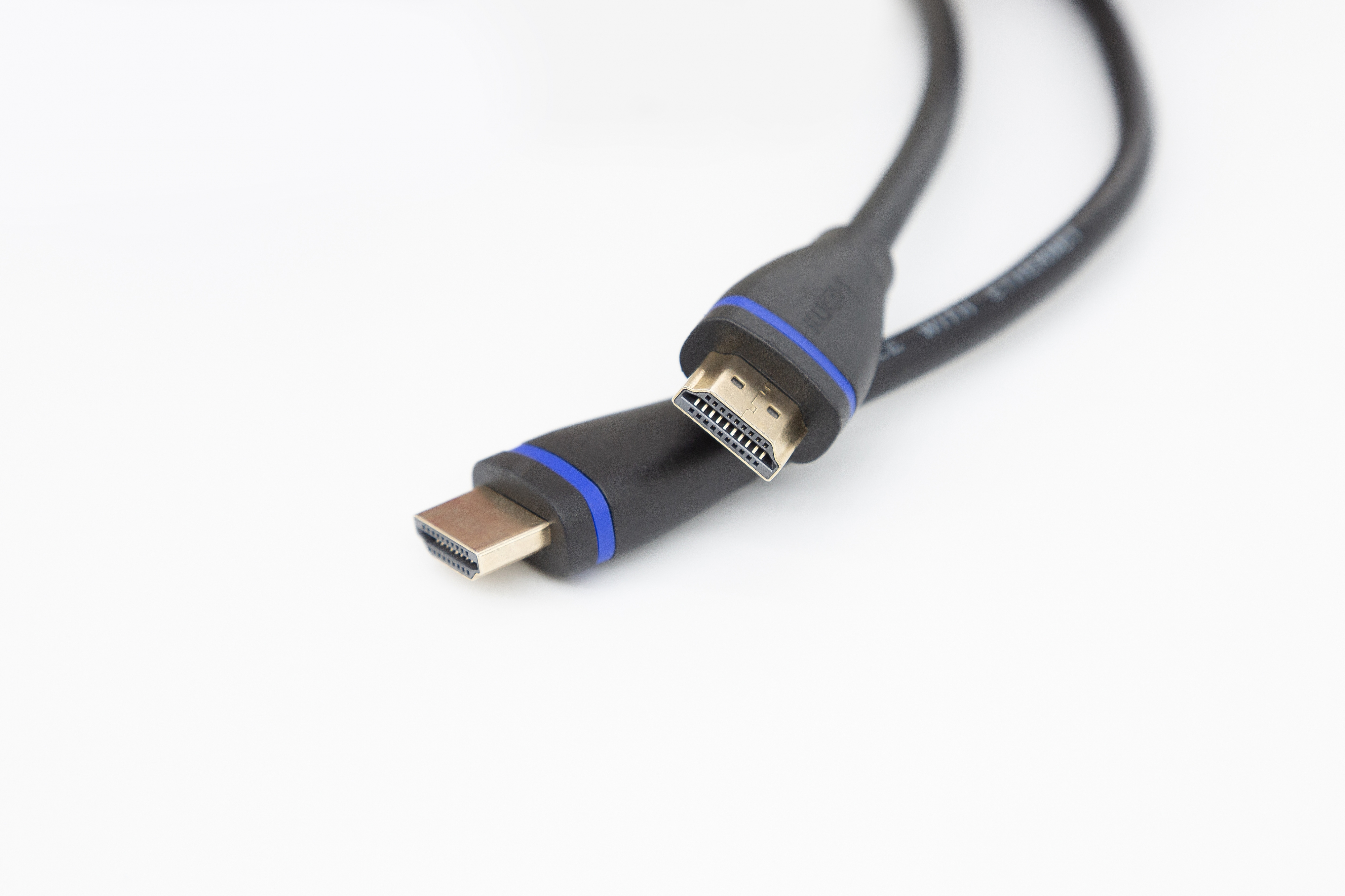 HDMI-Kabel mit blauen Akzenten, Nahaufnahme auf weißem Hintergrund. Ein Stecker ist scharf.