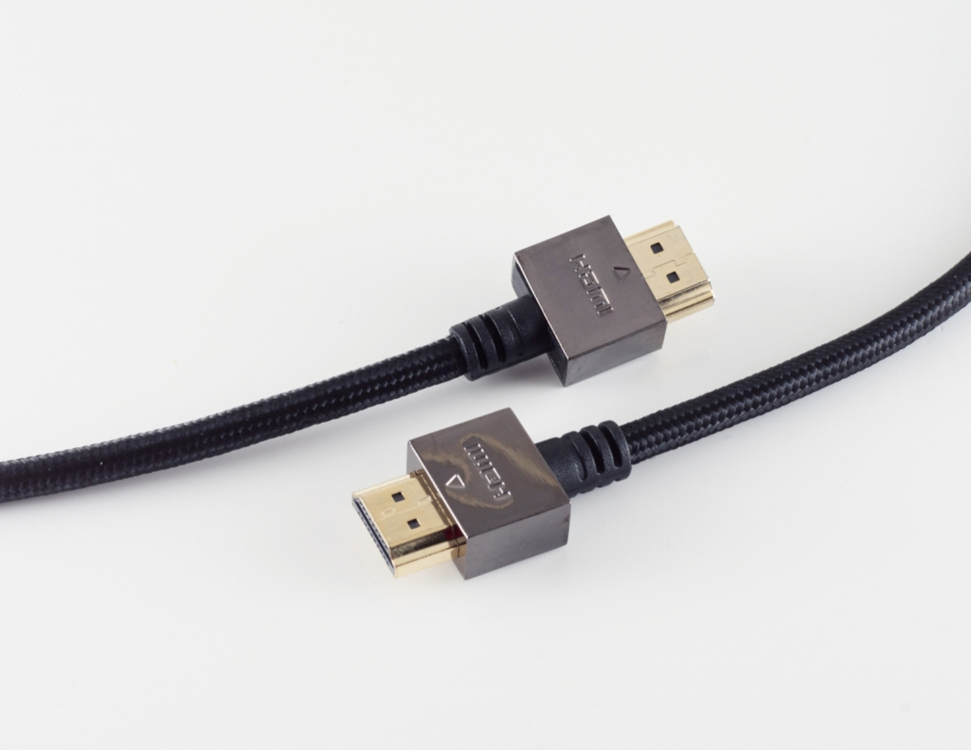 Zwei HDMI-Kabel mit schwarzen geflochtenen Hülsen und goldfarbenen Steckern vor weißem Hintergrund.